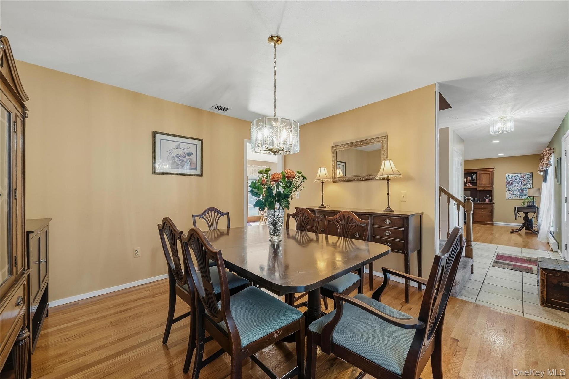 Hardwood flooring, chandelier lighting, built-in cabinetry, and a staircase with a wooden handrail