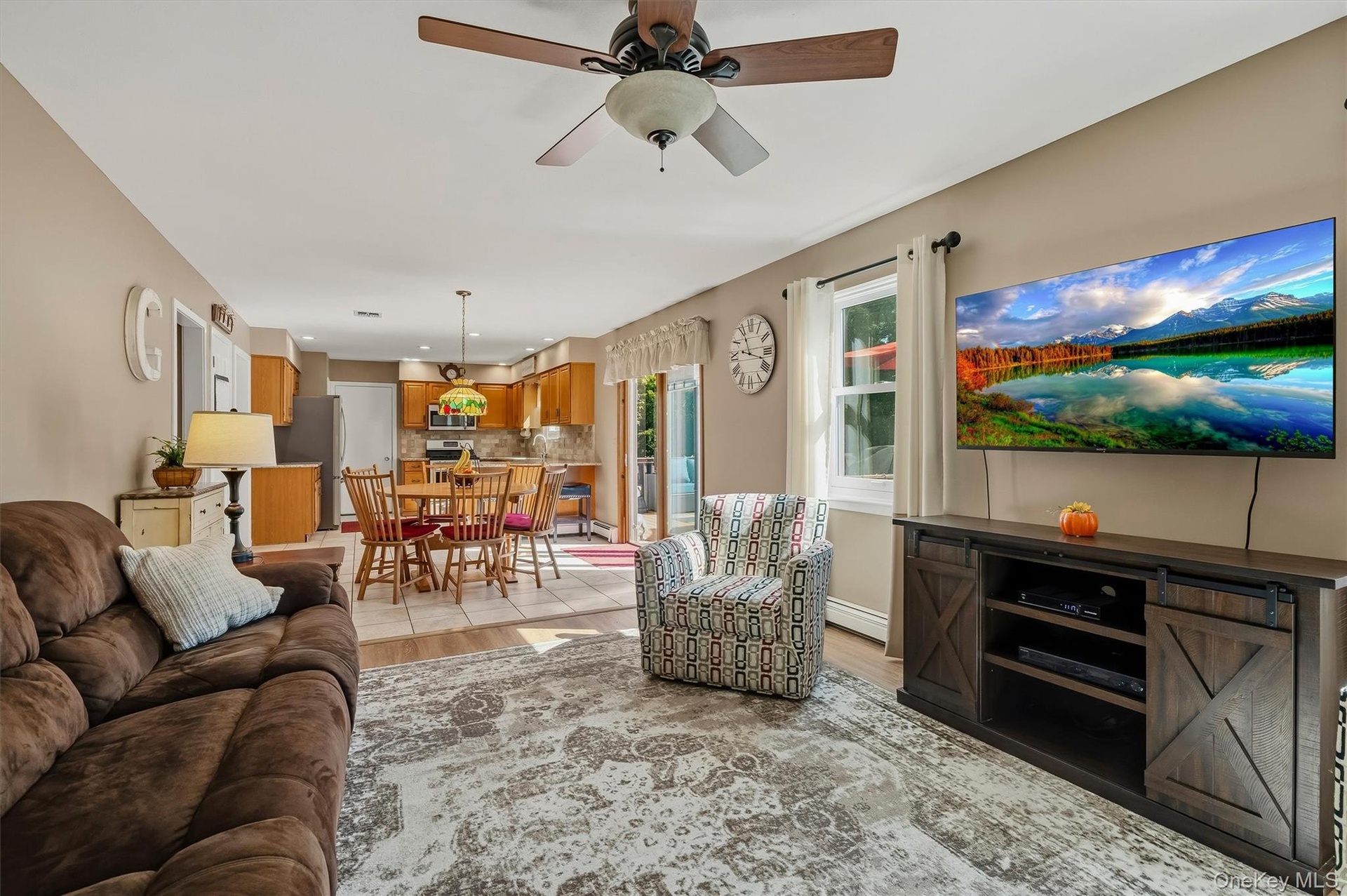 Open-concept living space featuring a ceiling fan, wall-mounted television, and wood-finish media console