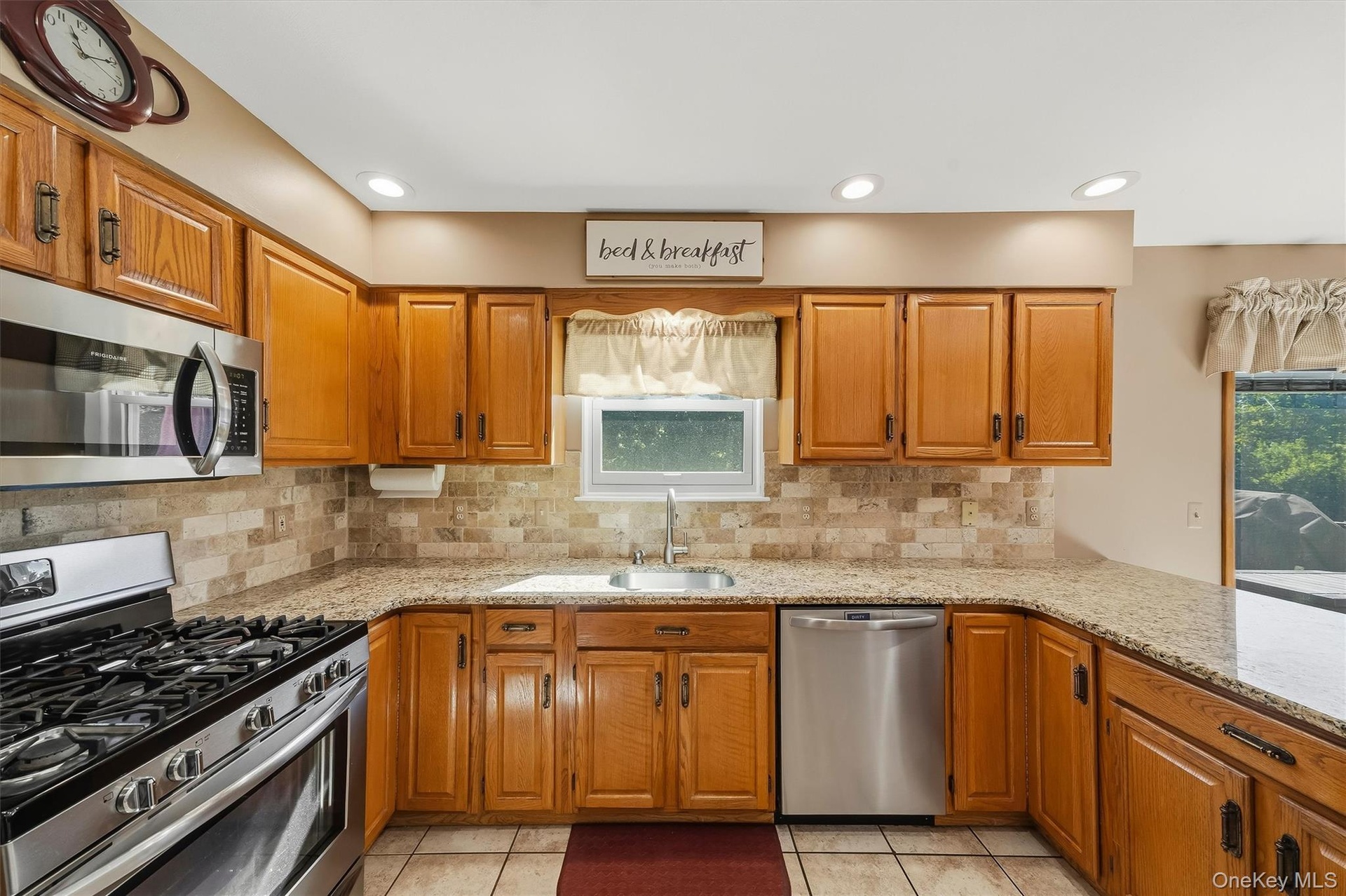 Kitchen featuring wood cabinetry, stainless steel appliances, granite-style countertops, and a tile backsplash