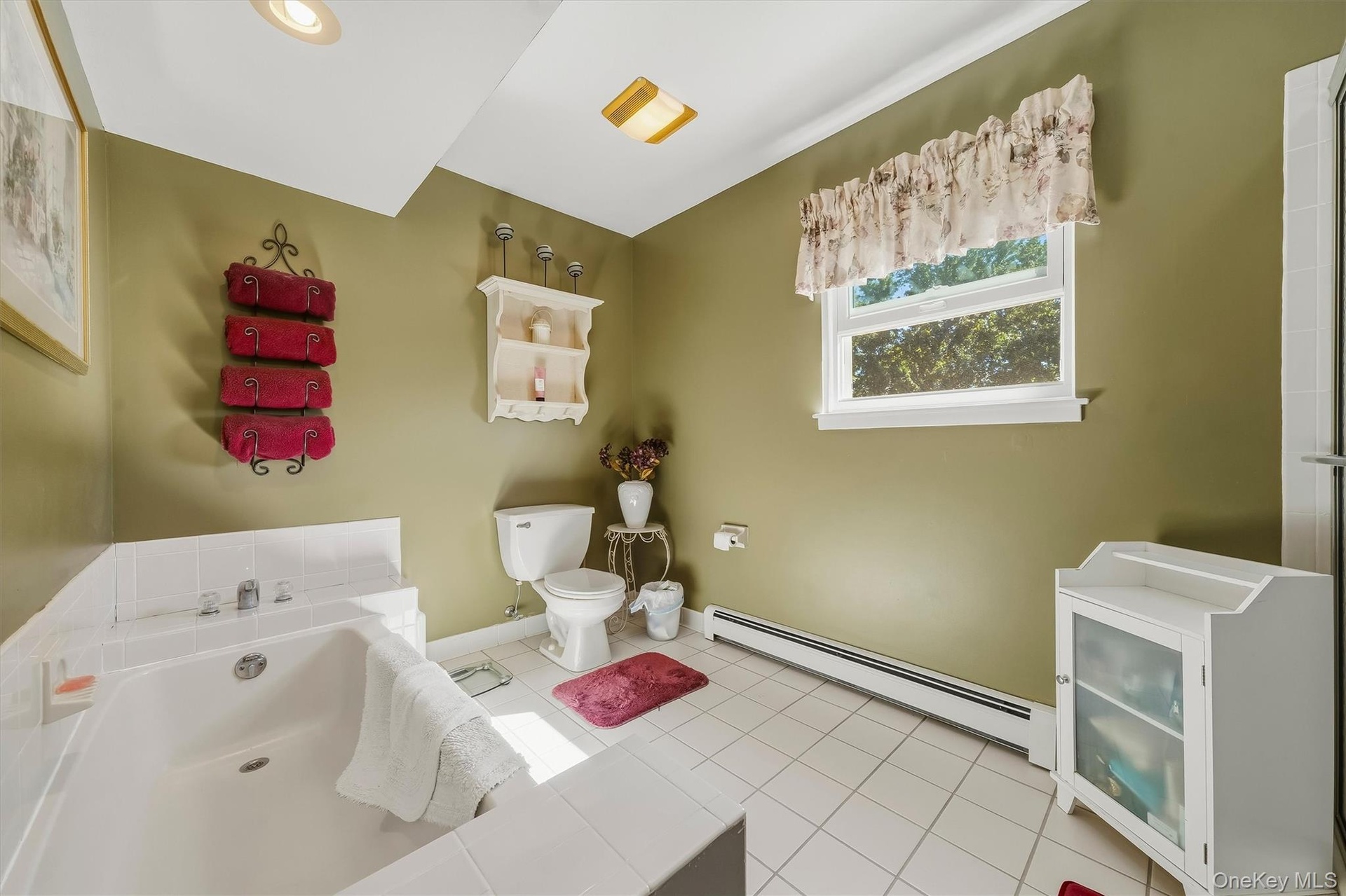 White tile flooring, built-in soaking tub, single window, recessed ceiling lighting, and a white toilet