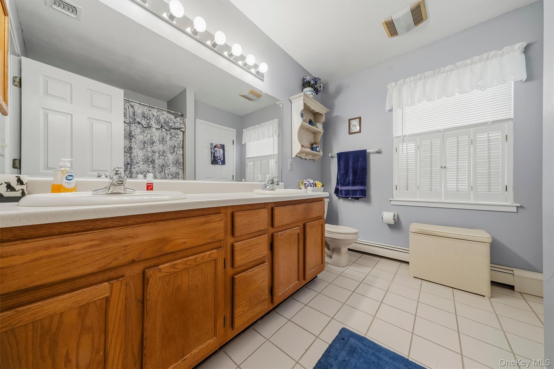 Double vanity with wood-finish cabinetry, dual sinks, and an expansive mirror