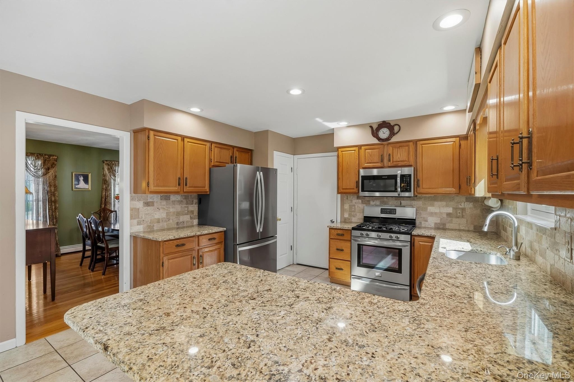 Kitchen featuring light wood cabinetry, stainless steel appliances, granite countertops, tile flooring, and recessed lighting
