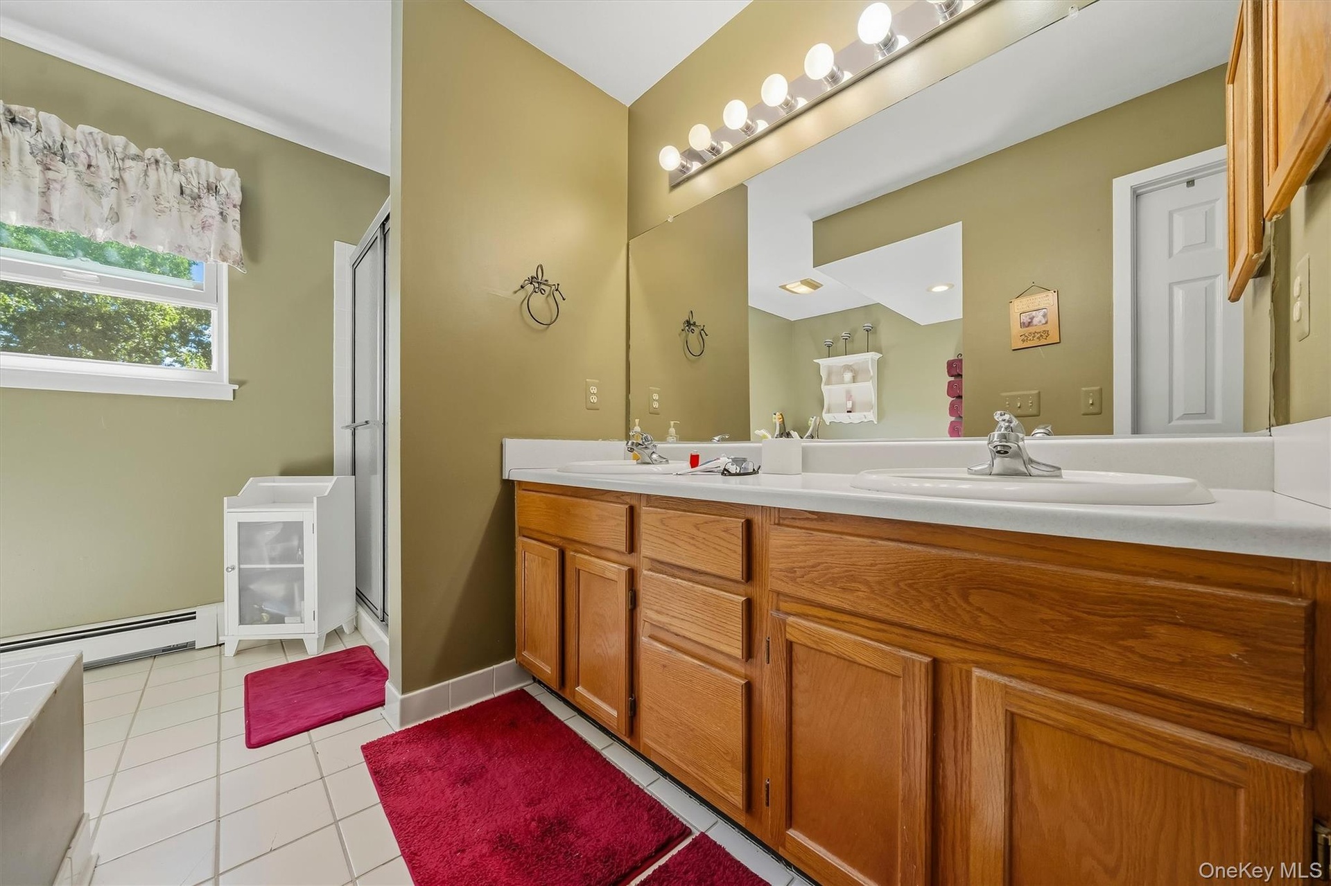 Dual vanity with wood-finish cabinetry, integrated sinks, and a full-width mirror