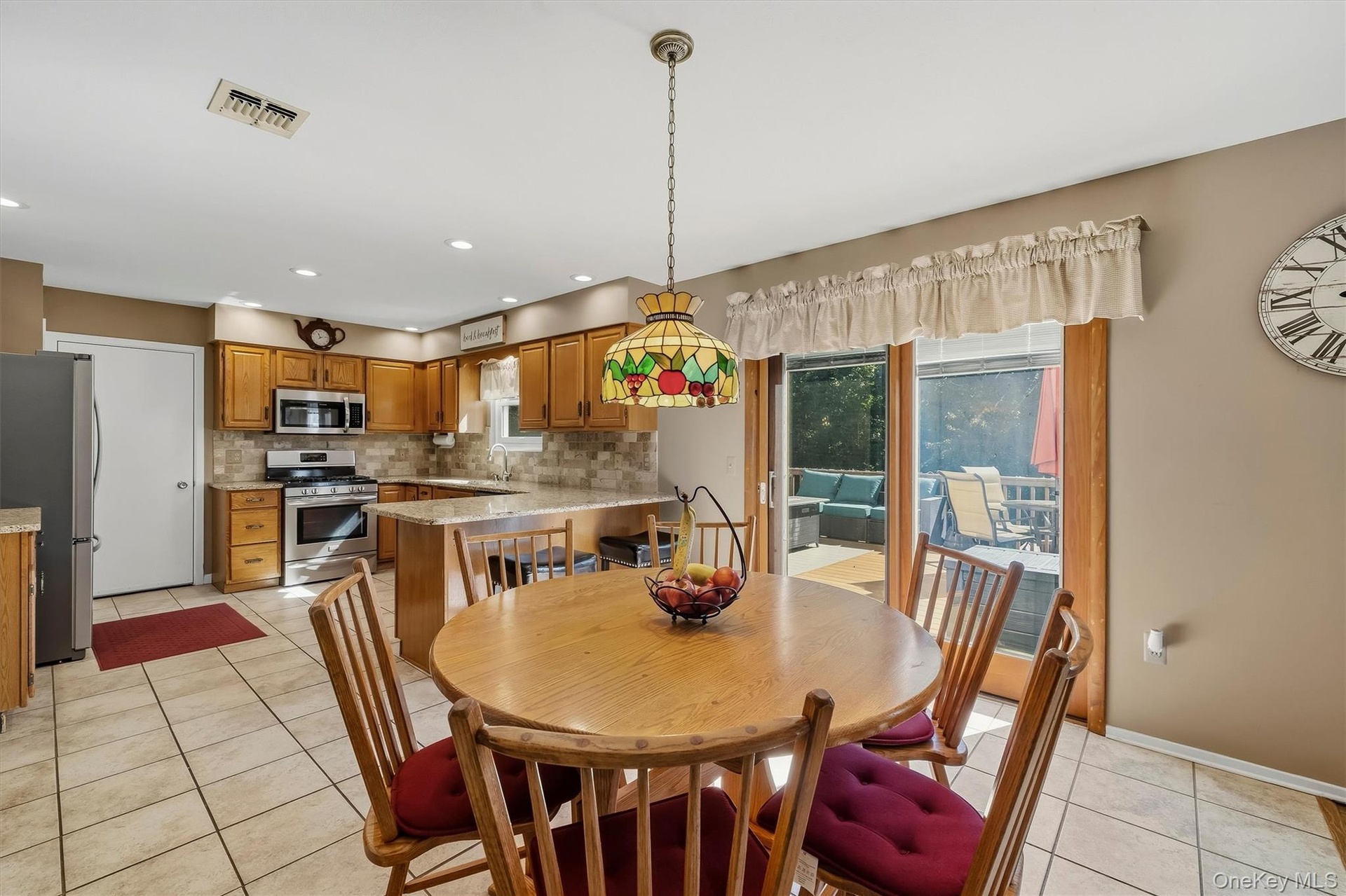 Kitchen featuring wood-finish cabinetry, tile flooring, stainless steel appliances, and a peninsula with countertop seating