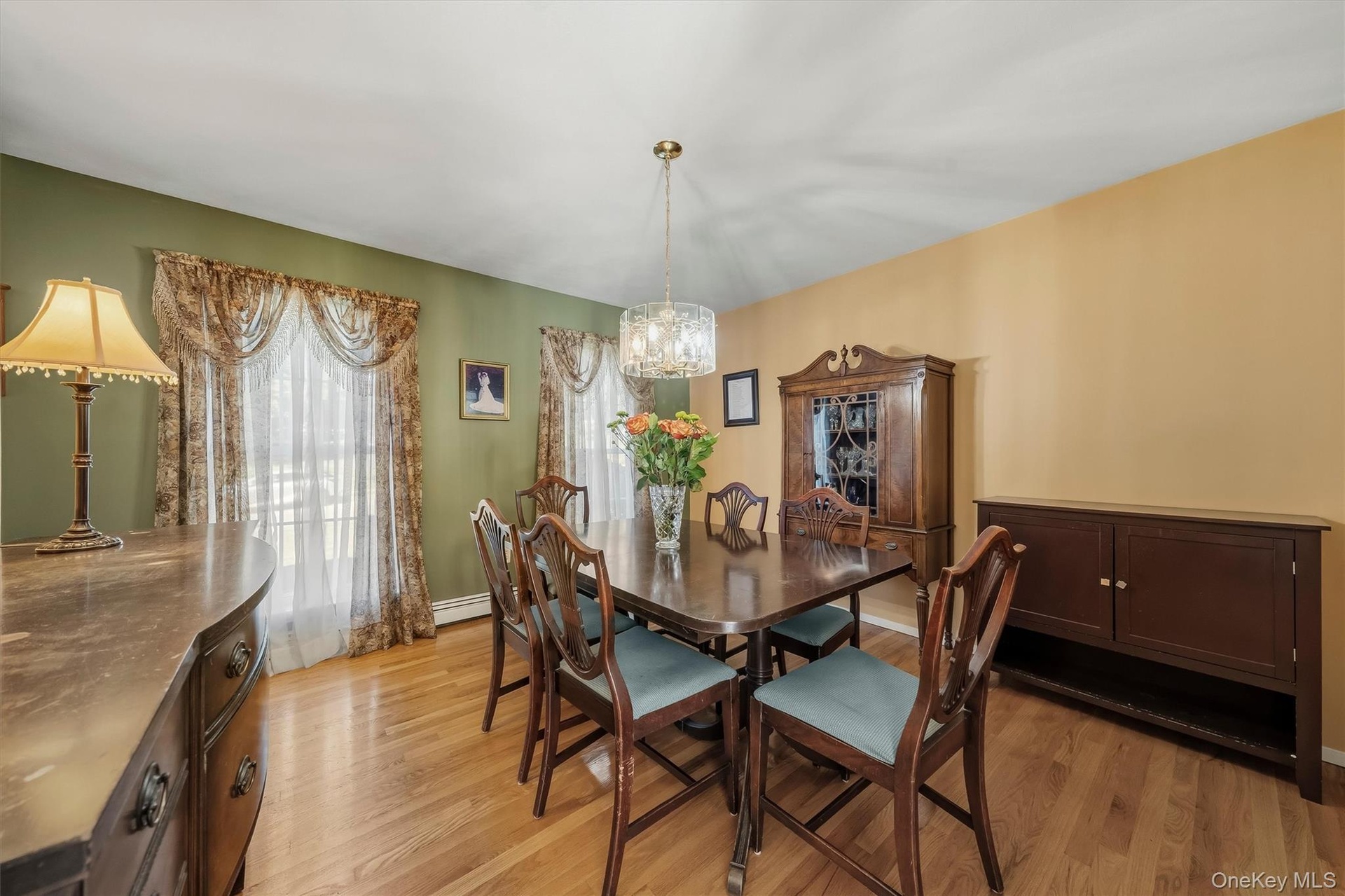 Hardwood flooring throughout, with a crystal chandelier, and large window with decorative valance