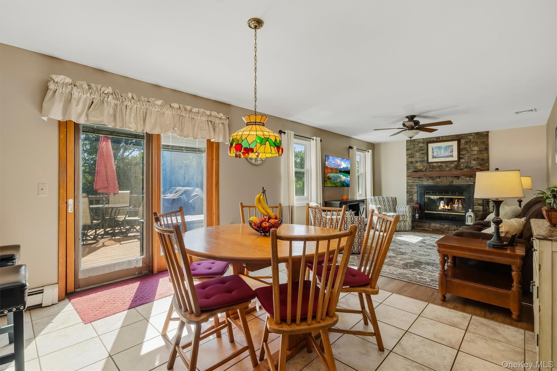 Bright dining area featuring a wood-finish table with matching spindle-back chairs, ceramic tile flooring, and abundant natural light from French door