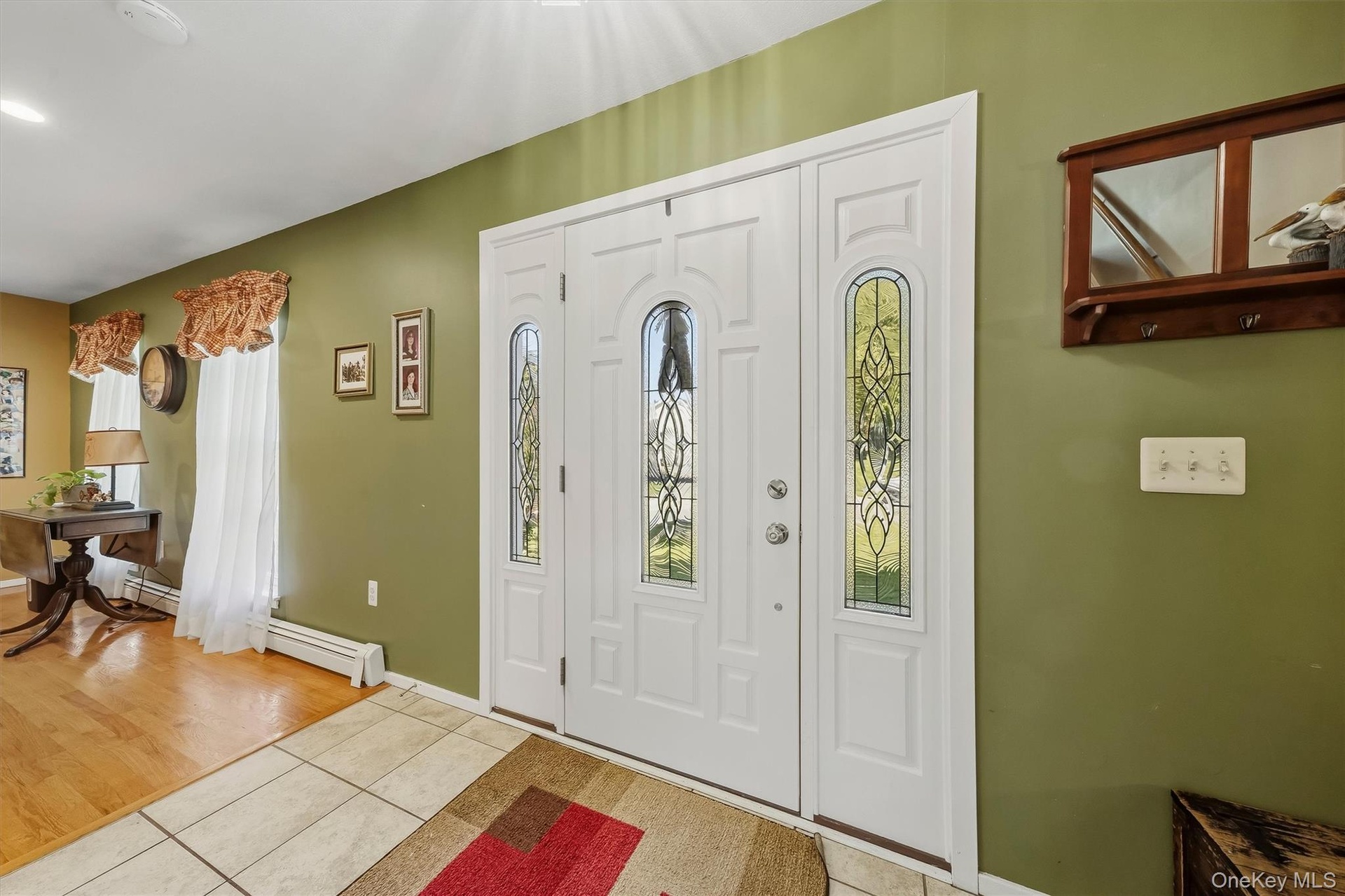 Entryway featuring a white double door with decorative glass inserts, ceramic tile flooring, and wood-finish flooring