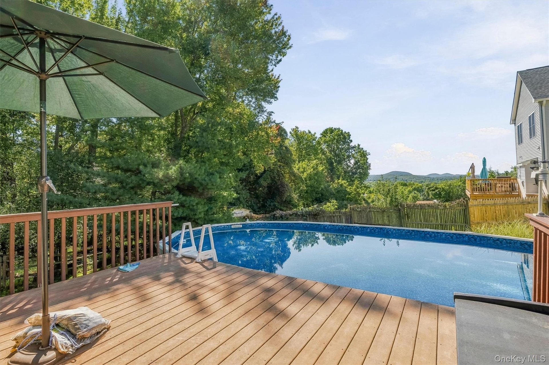 Expansive wood deck with a built-in swimming pool and wood railing