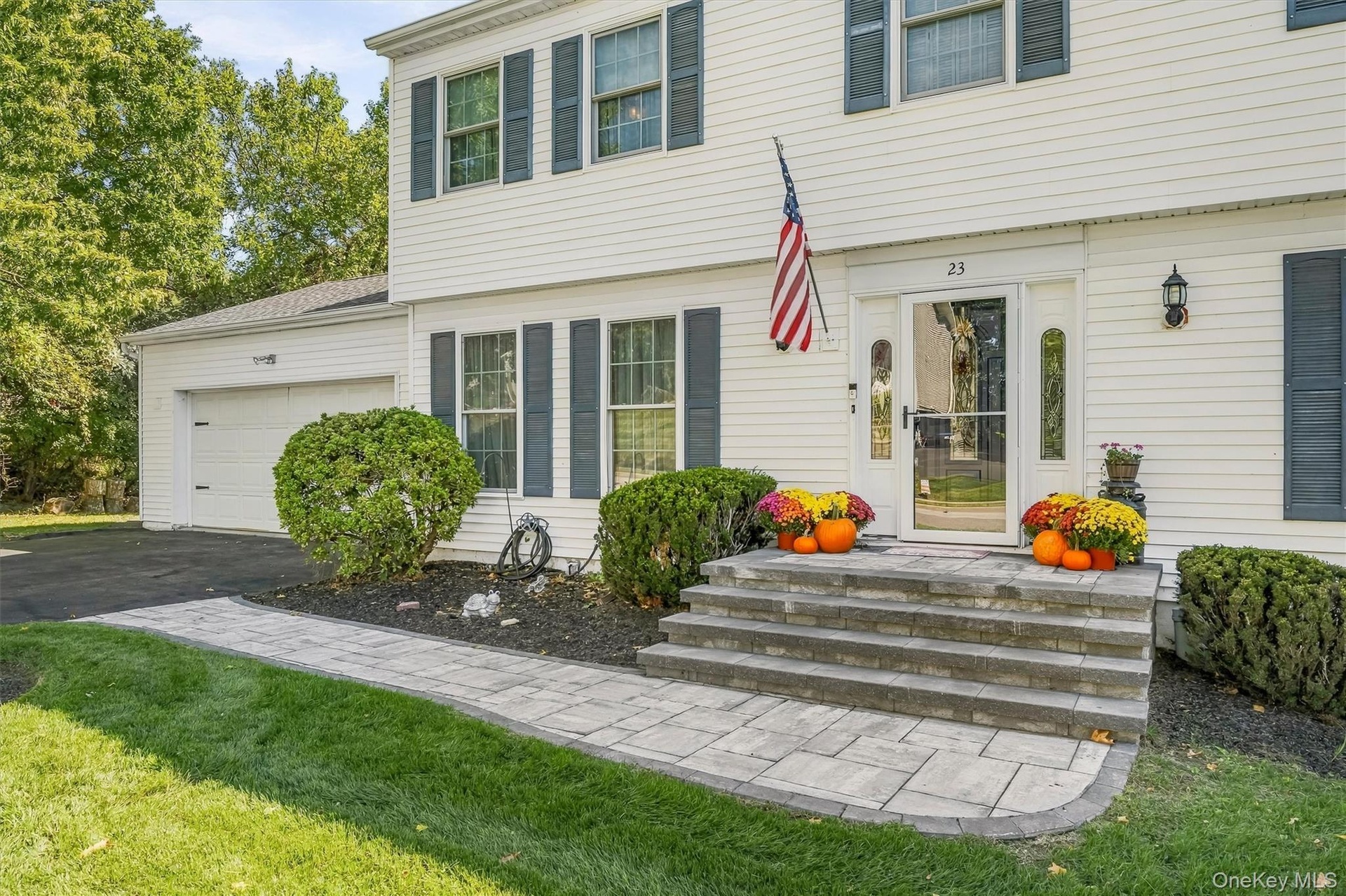 Welcoming front elevation featuring a two-story Colonial design with white horizontal siding, multi-pane windows, and a covered entry portico with sto