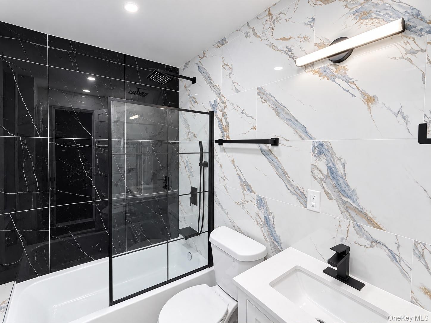Bathtub with black-framed glass shower enclosure, black tiled shower surround, patterned wall tile, contemporary vanity with integrated sink, and matt