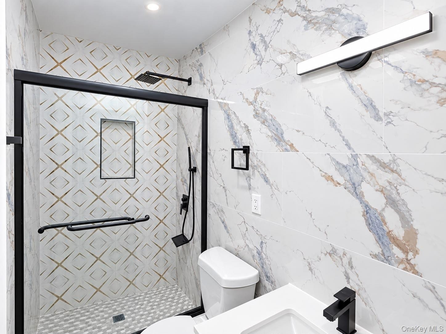 Walk-in shower with black-framed glass enclosure, patterned tile shower surround, and a rain showerhead