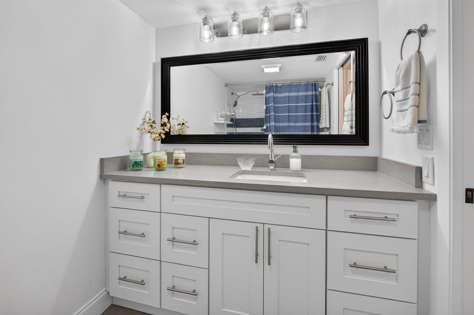 White vanity with shaker-style cabinetry, a built-in rectangular sink, and a countertop