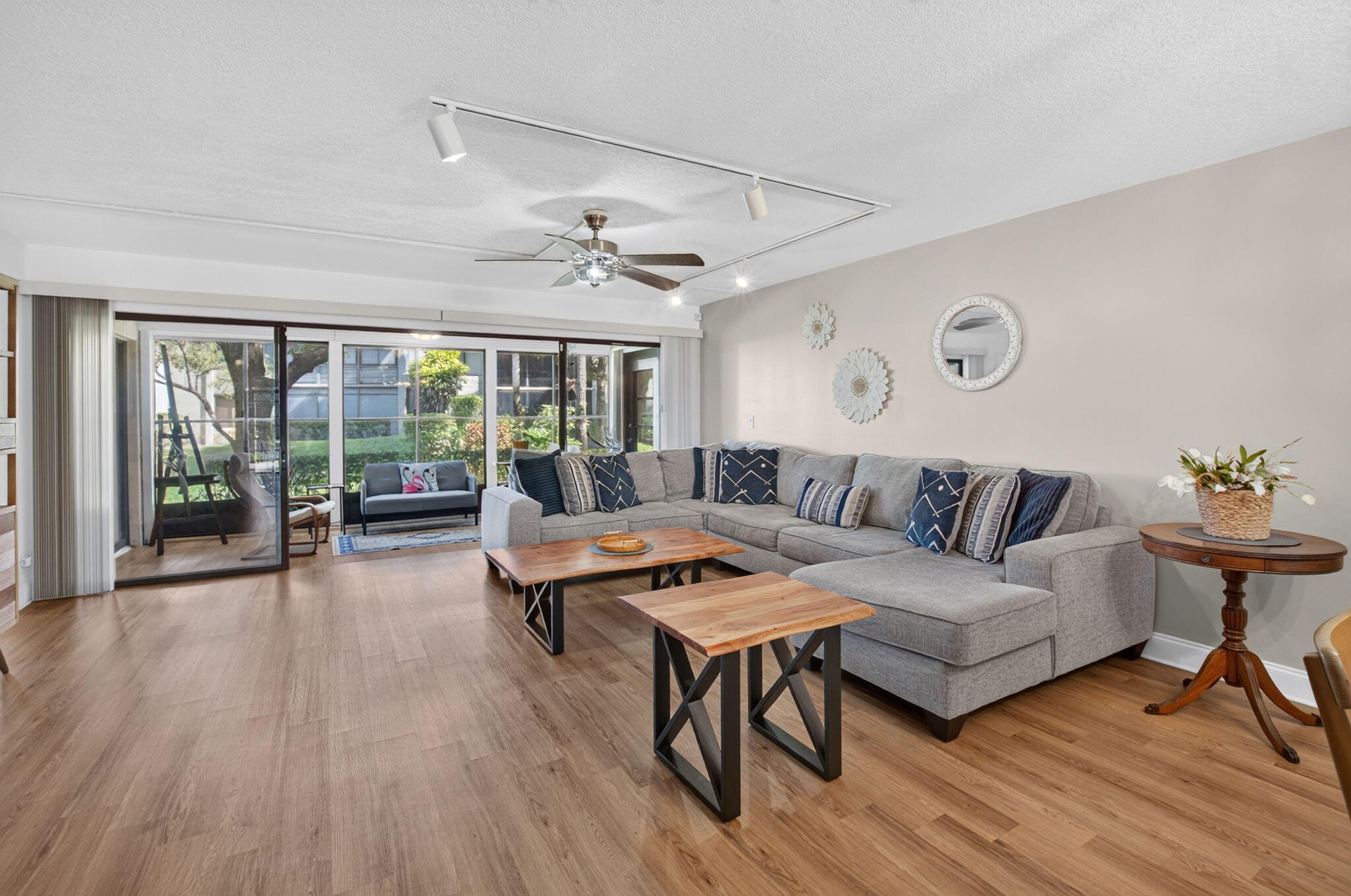 Expansive living area featuring wood-finish flooring, a ceiling fan, and track lighting