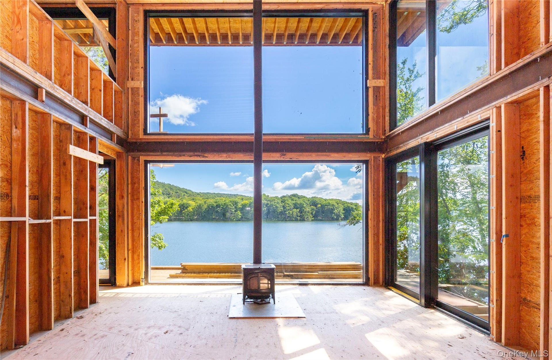 Inside, the main level is defined by a centered wood-burning stove that aligns with the window mullions, creating the illusion of one unbroken wall of
