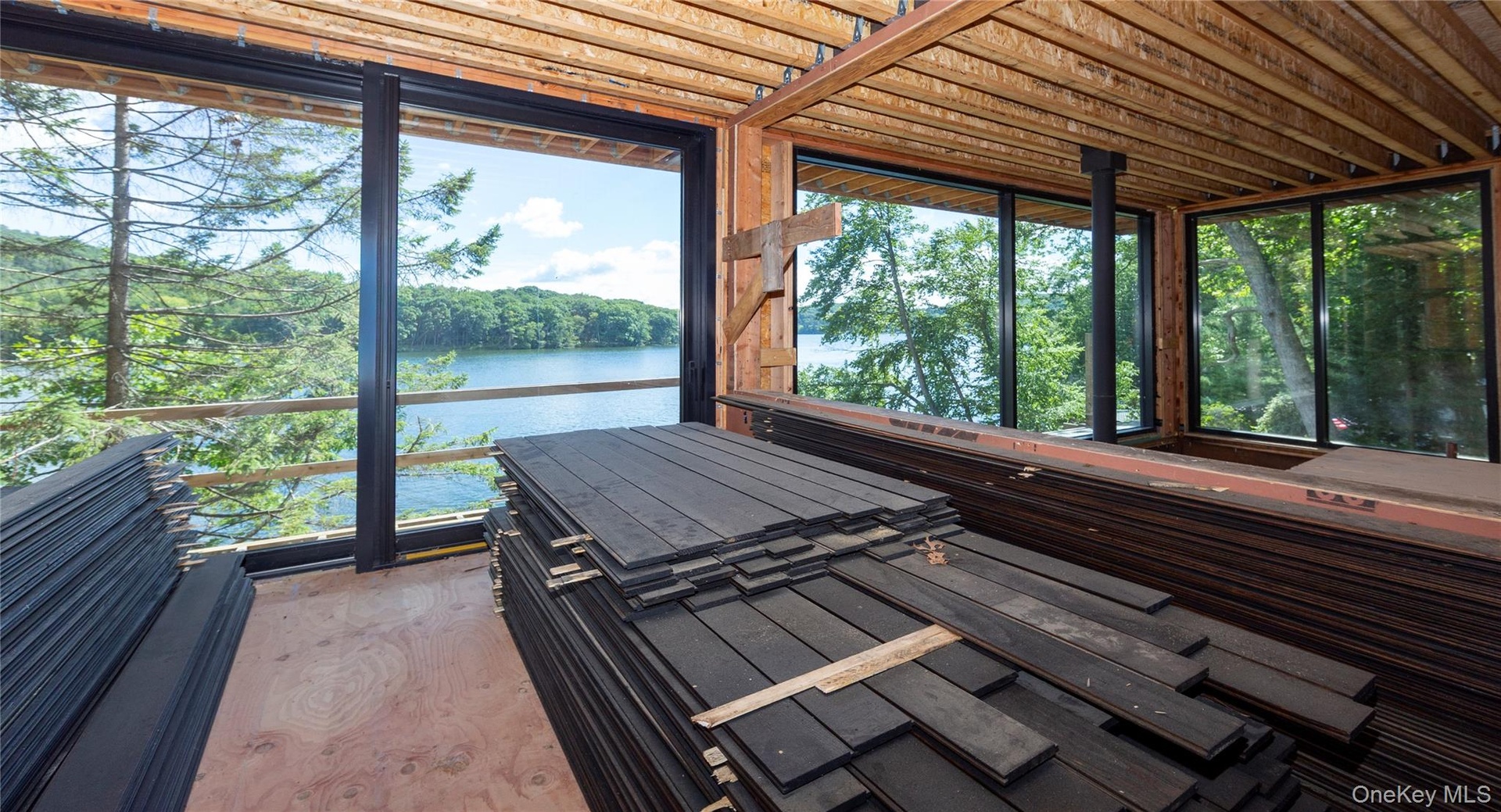 Materials already on site include the exterior siding, stained and ready for installation, as well as stone façade materials for portions of the lower