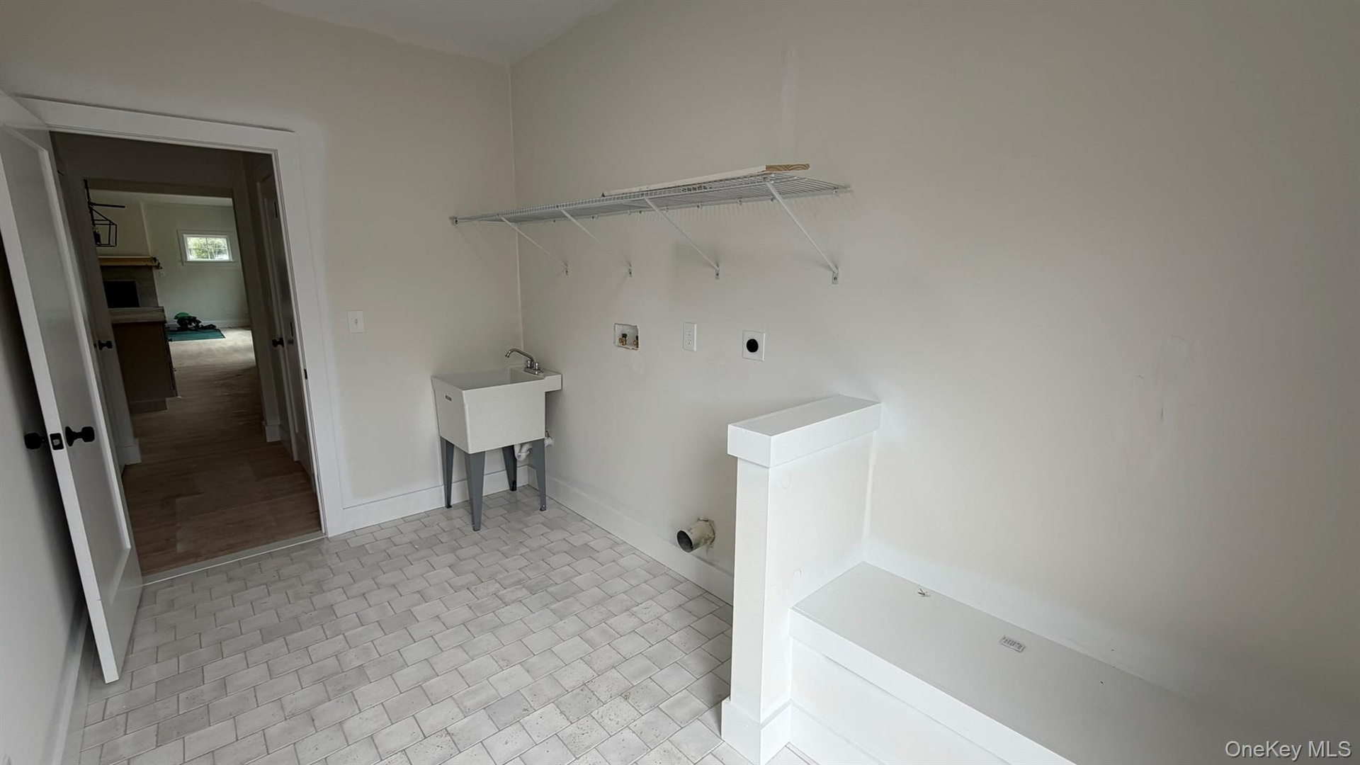 Tiled entry featuring a built-in bench, new shelving and a utility sink.