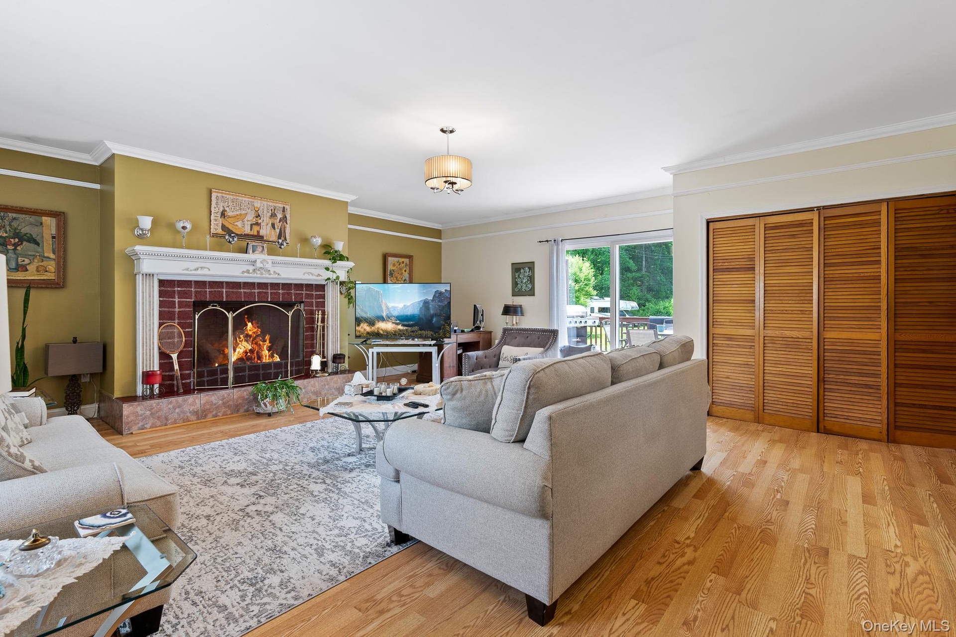Living area featuring light wood finished floors, crown molding, and a tiled fireplace