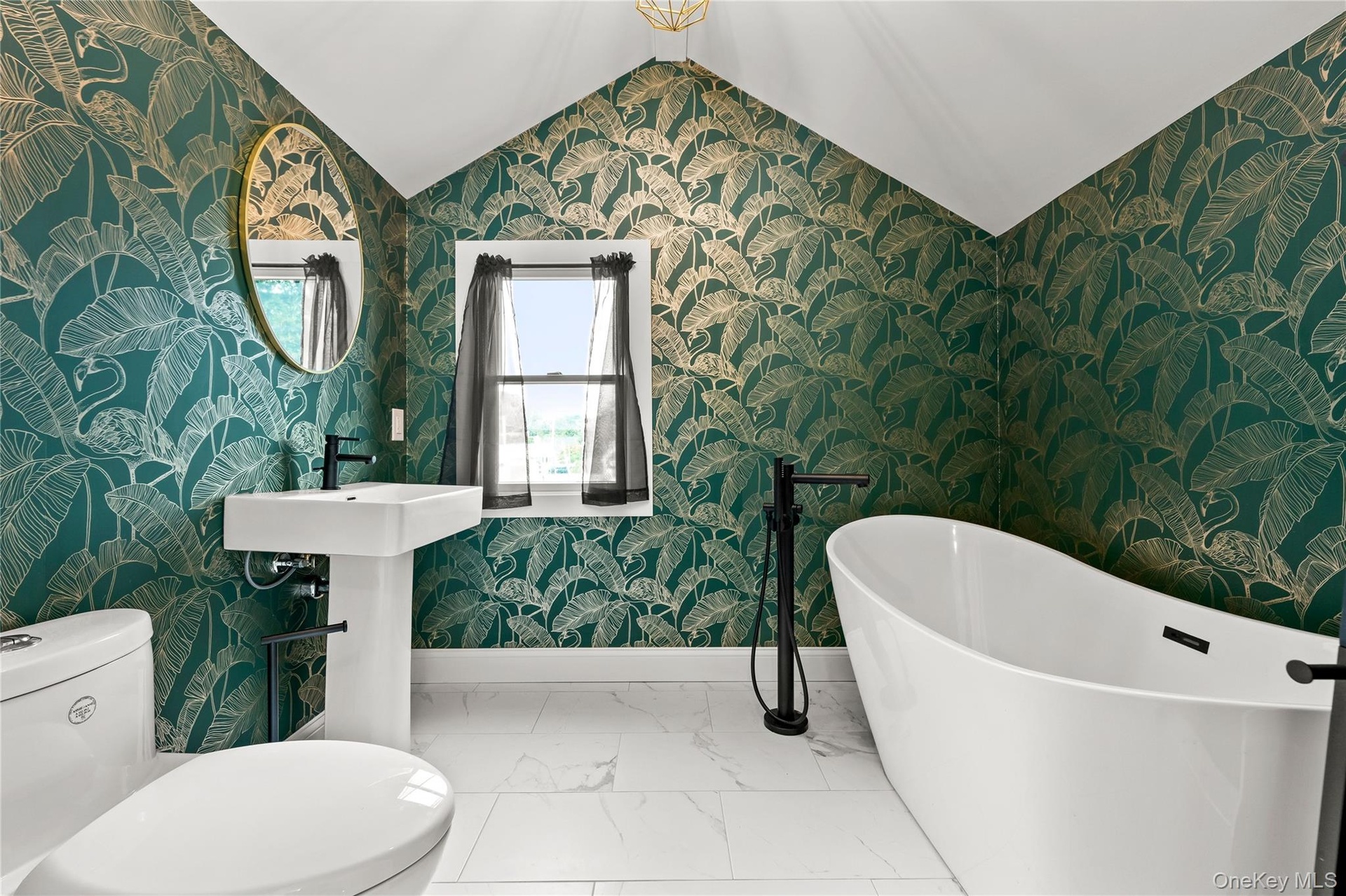 Pedestal sink with a matte black faucet, a freestanding bathtub with a floor-mounted fixture, and white tile flooring