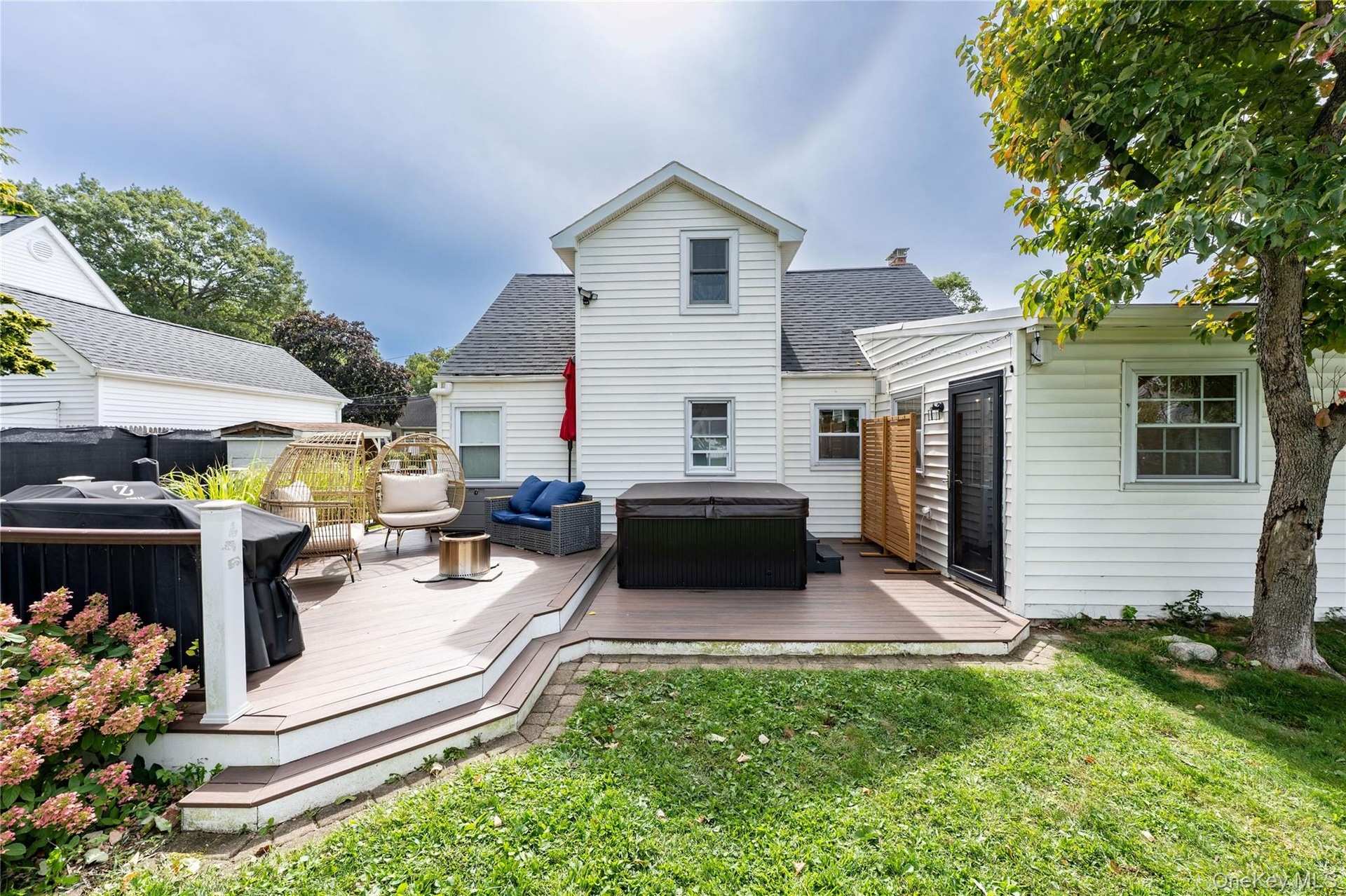 Rear view of the house with multi-level composite deck, white vinyl siding and fenced backyard