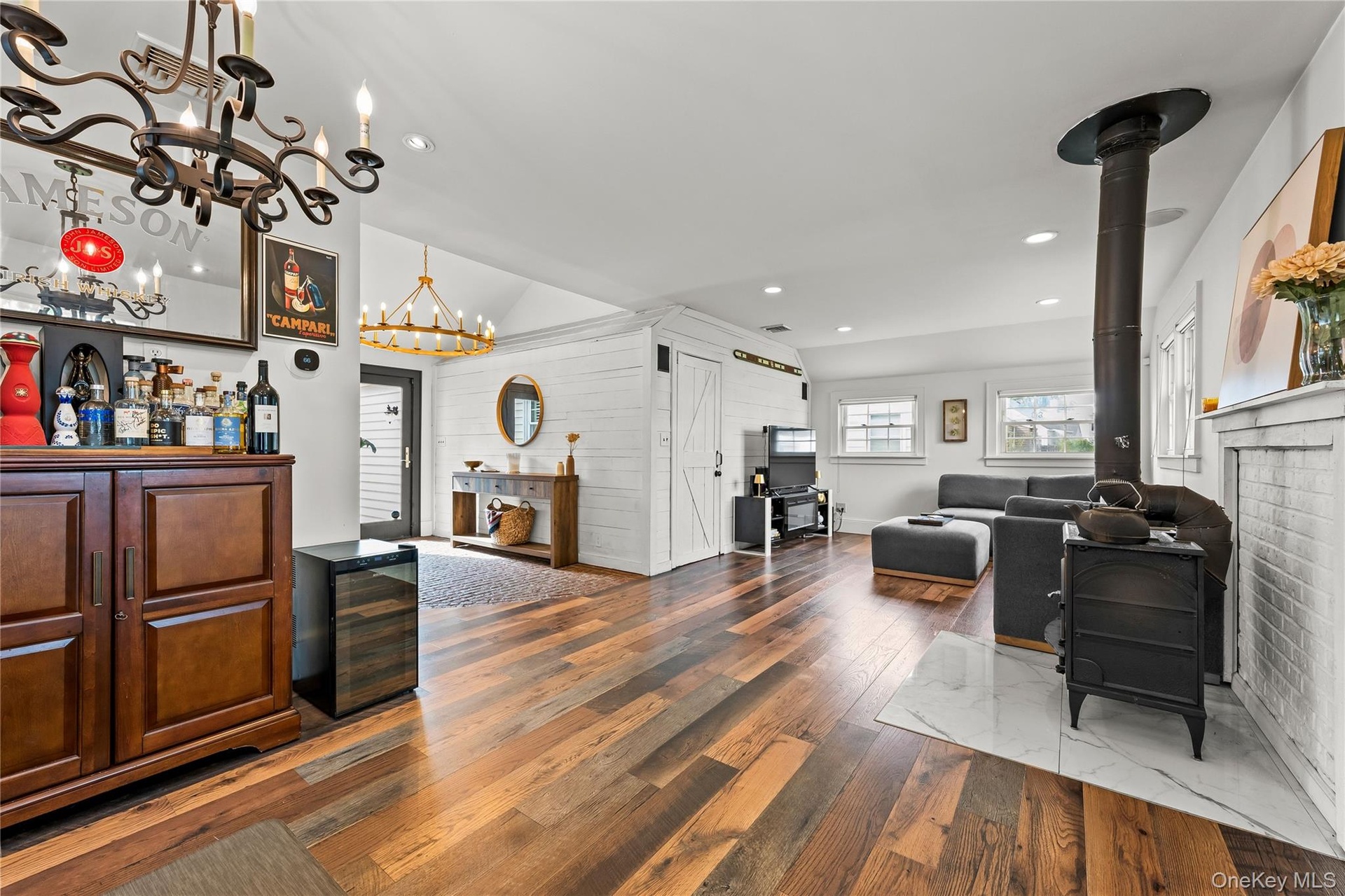 Open living room with hardwood floors, wood-burning stove, built-in bar cabinetry and recessed lighting flowing to the dining area