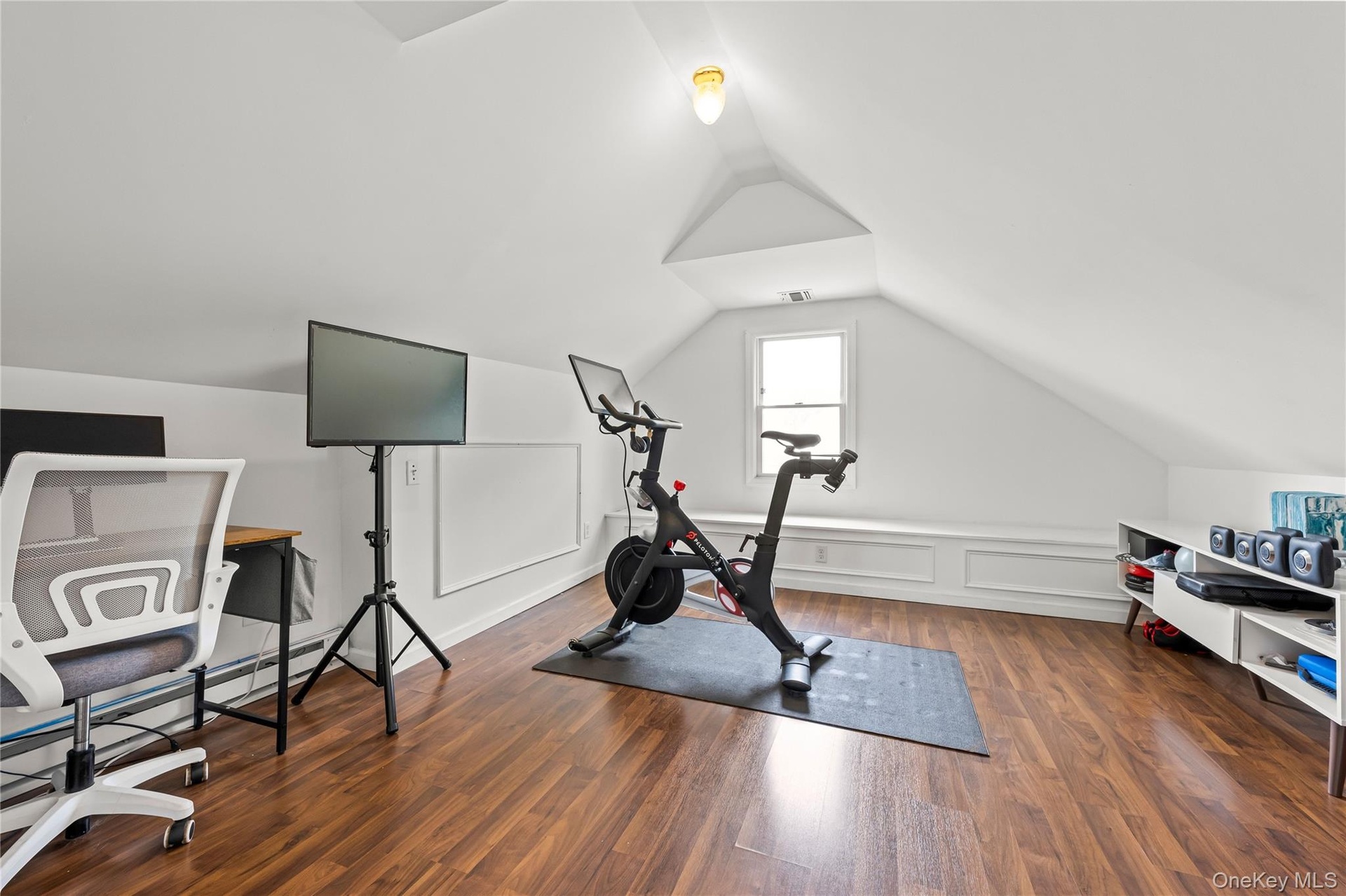Attic space featuring wood-finish flooring, vaulted ceiling, built-in window bench, and a dormer window