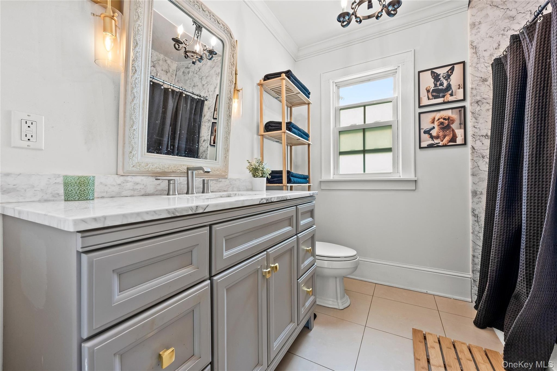 Bathroom featuring a light gray vanity with gold-tone hardware, a white countertop, and a vanity mirror with integrated lighting