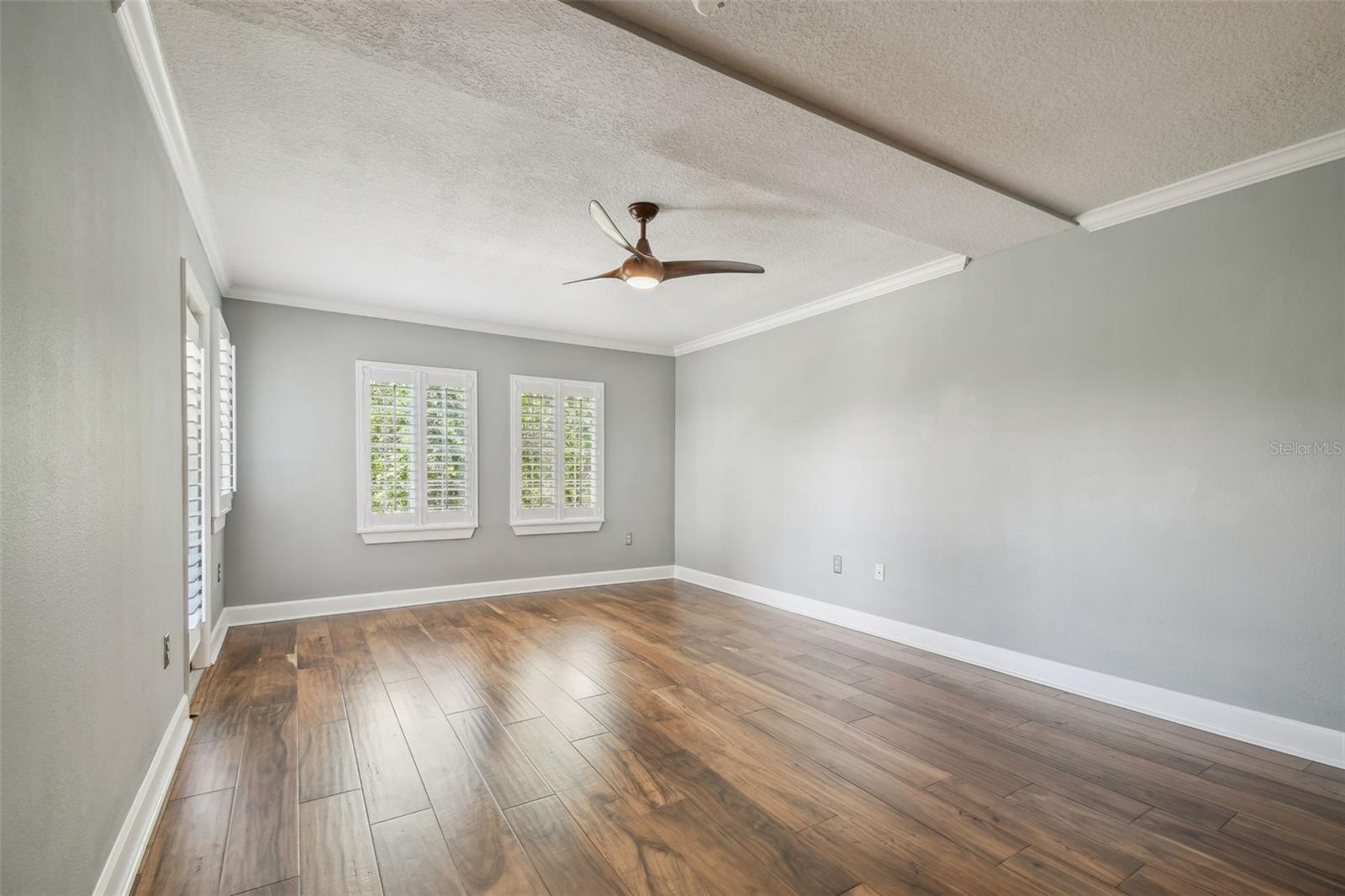 Spacious primary suite with a door leading out to the enclosed balcony.