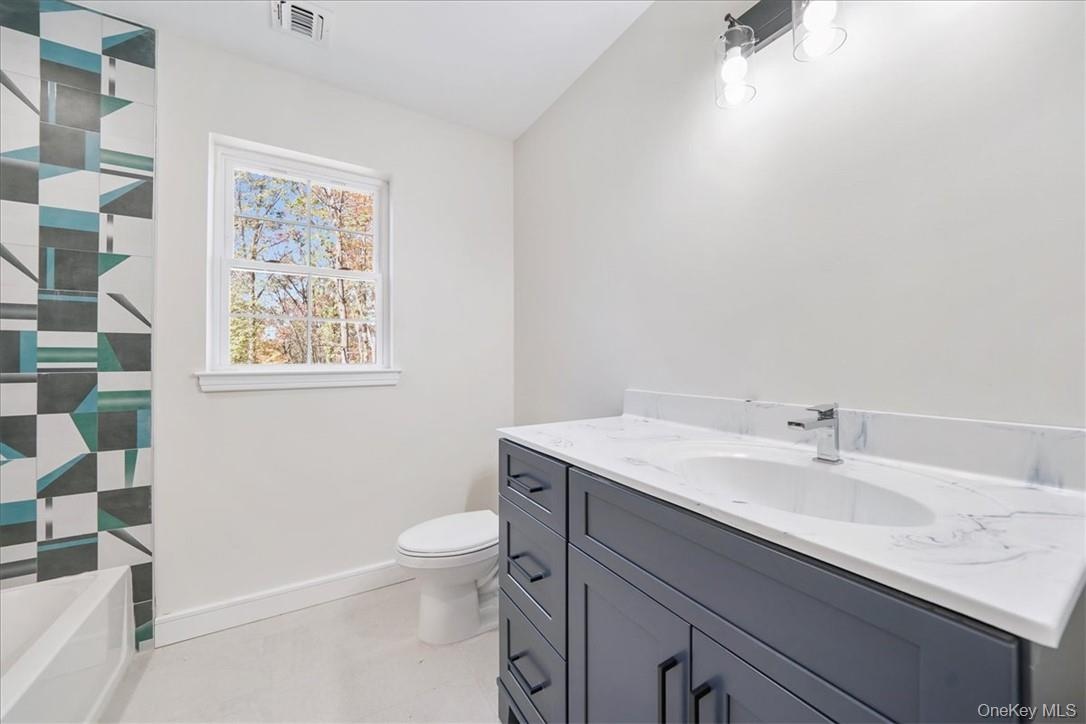 Bathroom with a shower, vaulted ceiling, vanity, and toilet