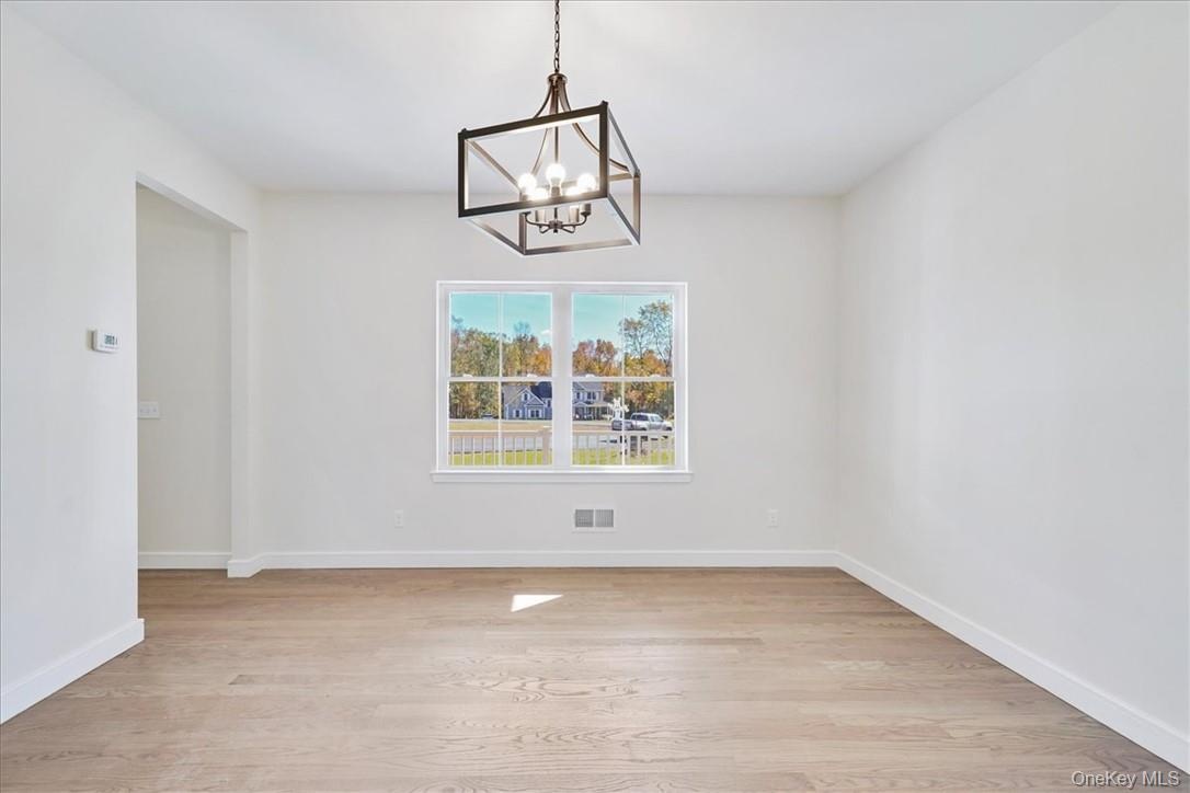 Unfurnished dining area with light wood-type flooring and an inviting chandelier