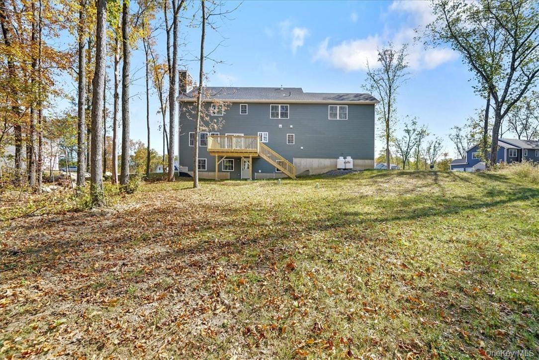 Rear view of house with a yard and a wooden deck