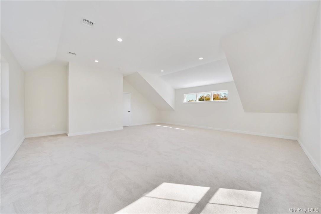 Bonus room with light carpet and vaulted ceiling