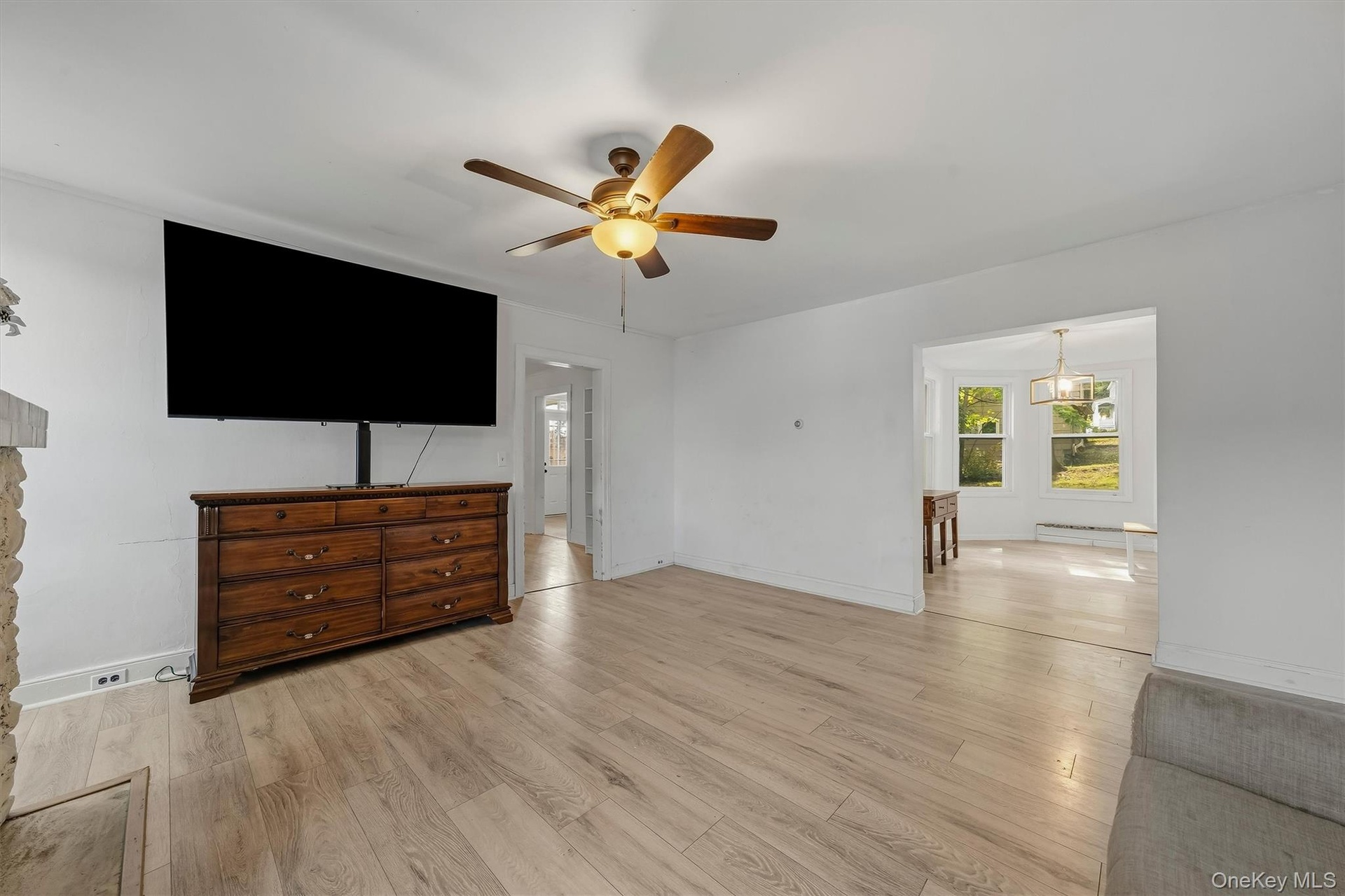 Light wood-finish flooring throughout, complemented by a ceiling fan with integrated lighting
