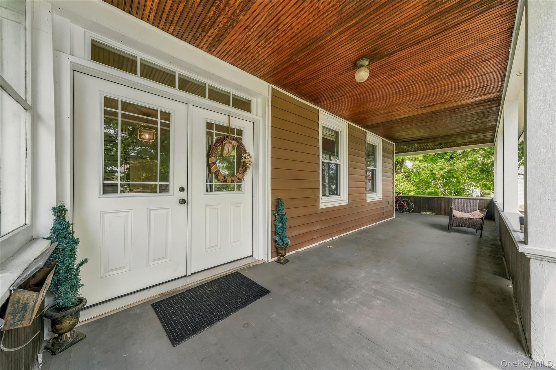 Covered porch featuring a wood-plank ceiling, white trim, and a gray floor
