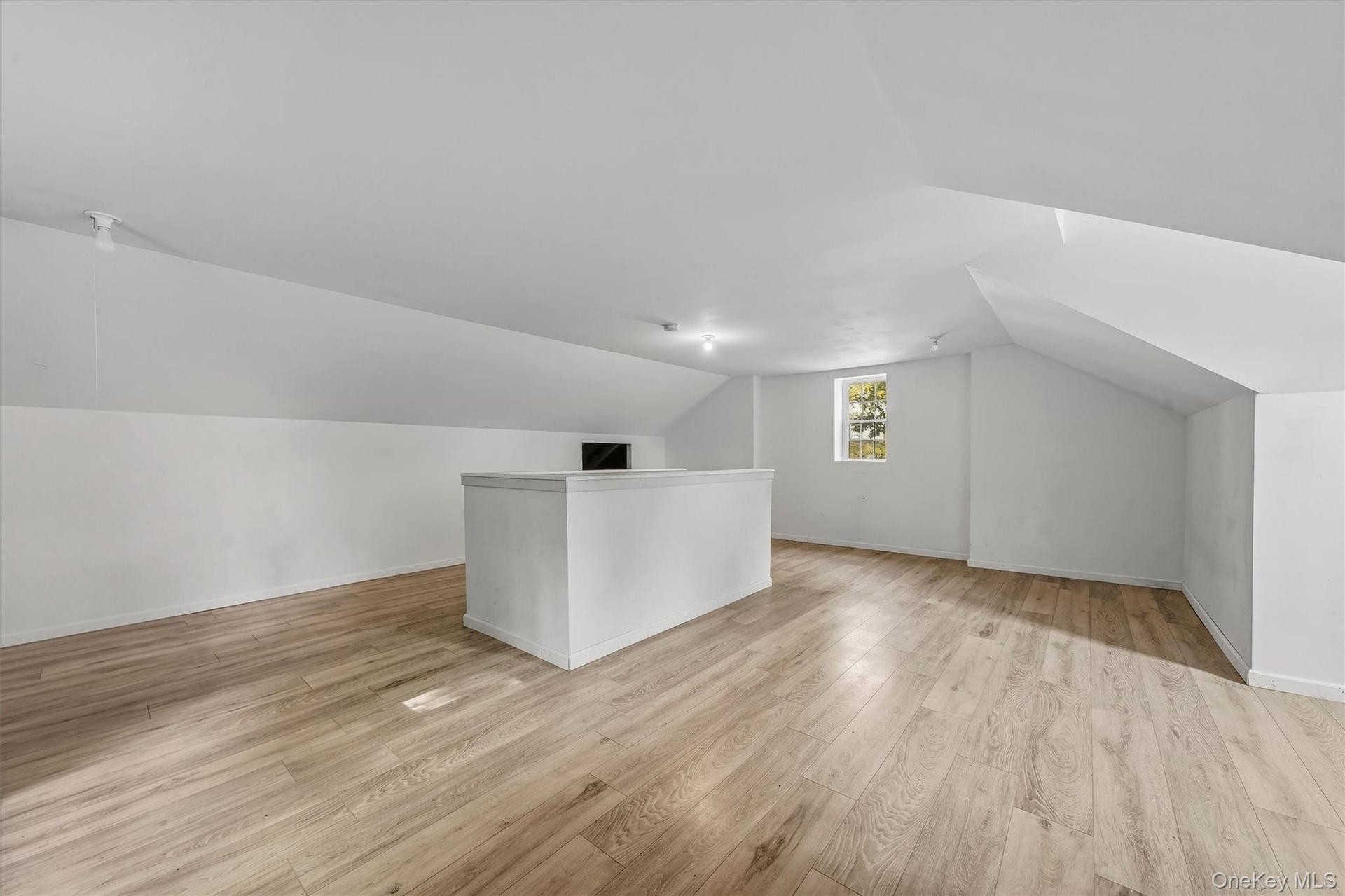 Spacious loft area featuring wood-finish flooring, recessed lighting, and a built-in half-wall partition