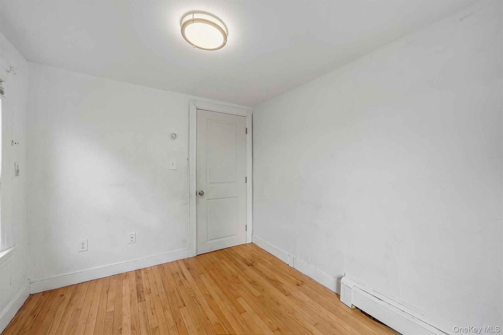 Hardwood flooring, painted walls, flush-mount ceiling light, and baseboard heating
