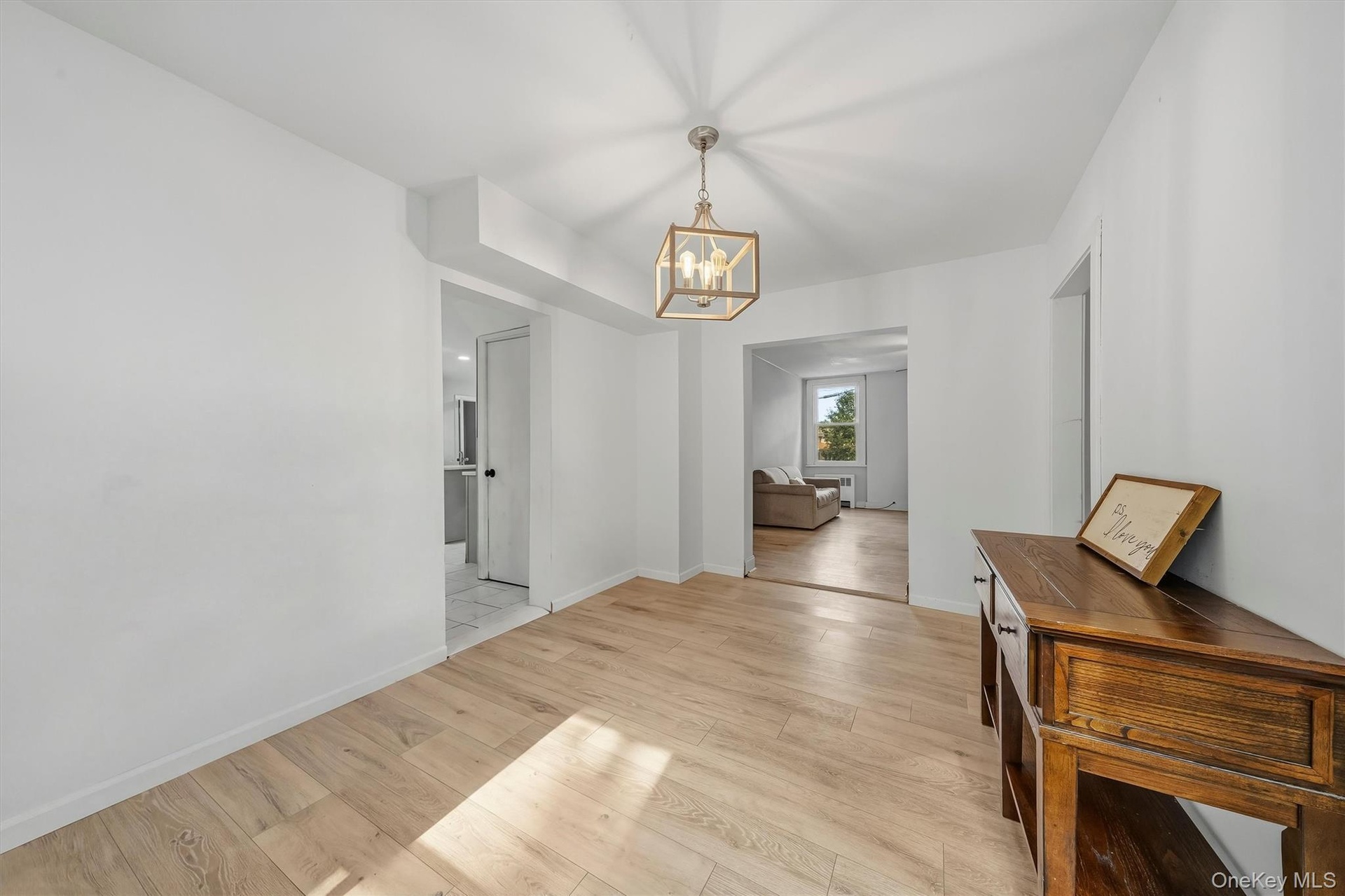 Wood-finish flooring throughout, a modern chandelier, and bright white wall finishes