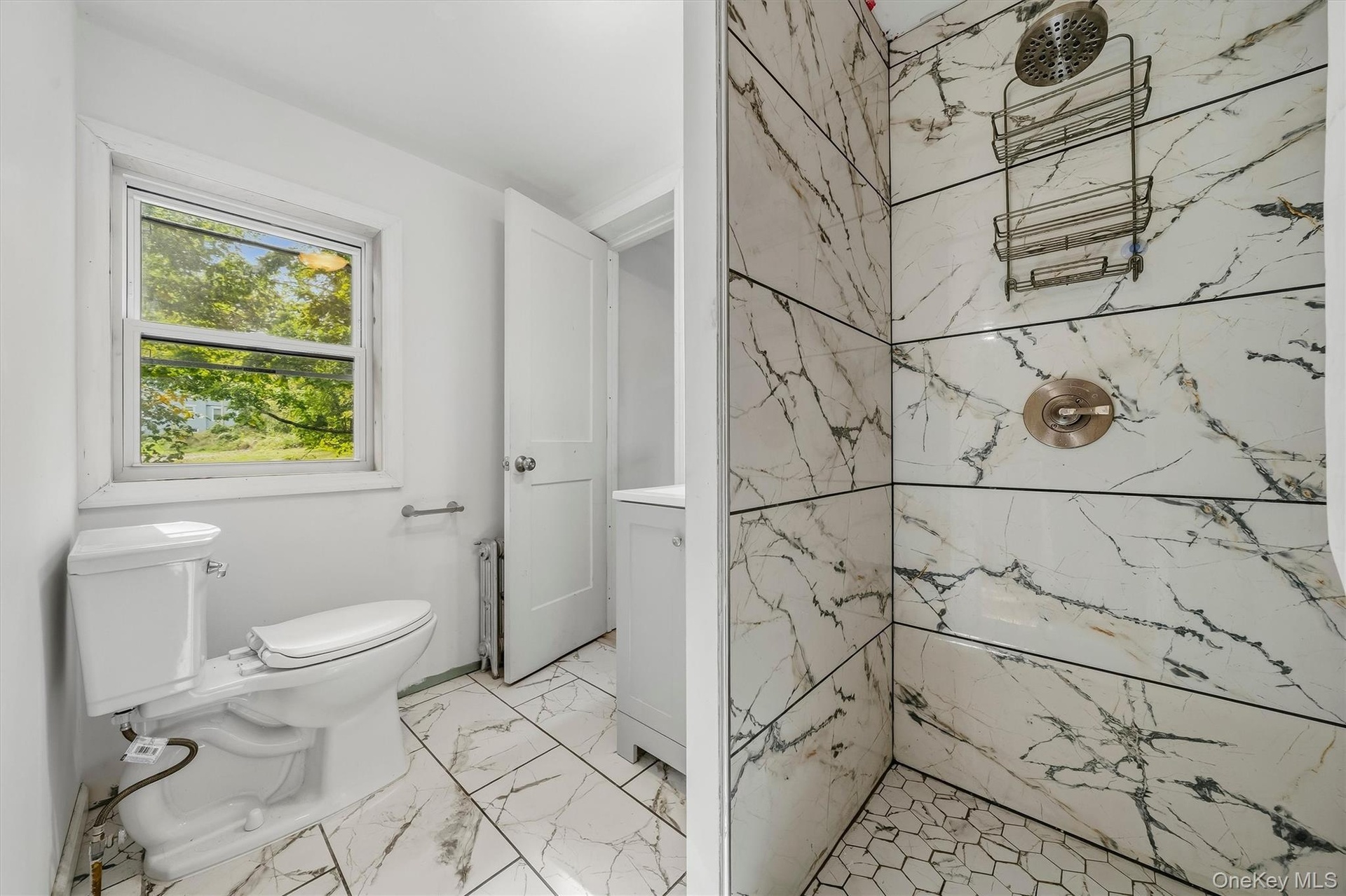 Bathroom featuring a tiled shower with a rain shower head, hexagonal floor tiles, and a window