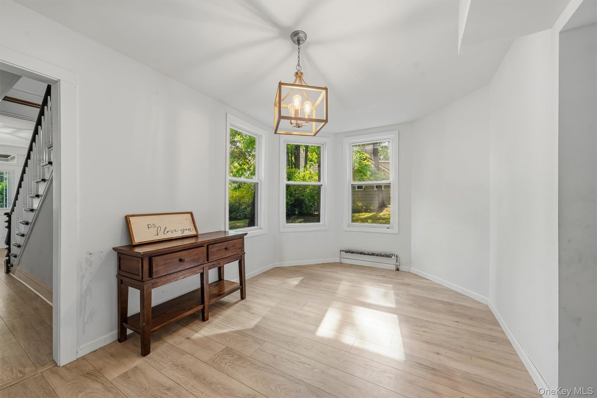 Light wood-finish flooring, white walls, three windows, and a ceiling-mounted light fixture