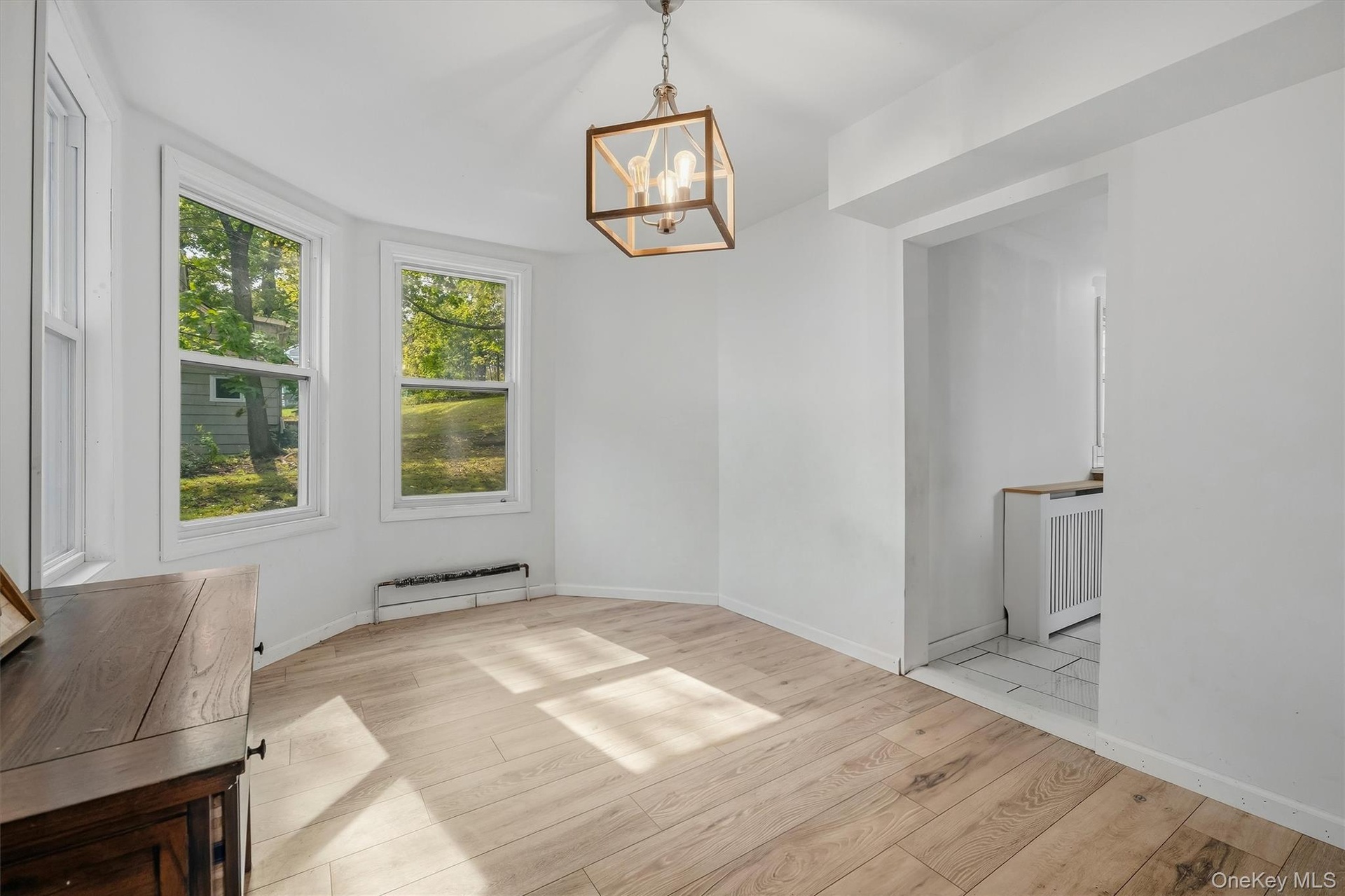 White walls, wood-finish flooring, and a contemporary chandelier