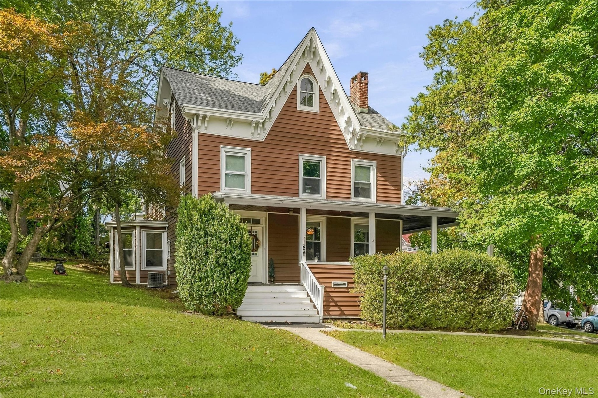 Victorian-style residence featuring brown siding with white trim, a covered front porch, and a prominent front gable