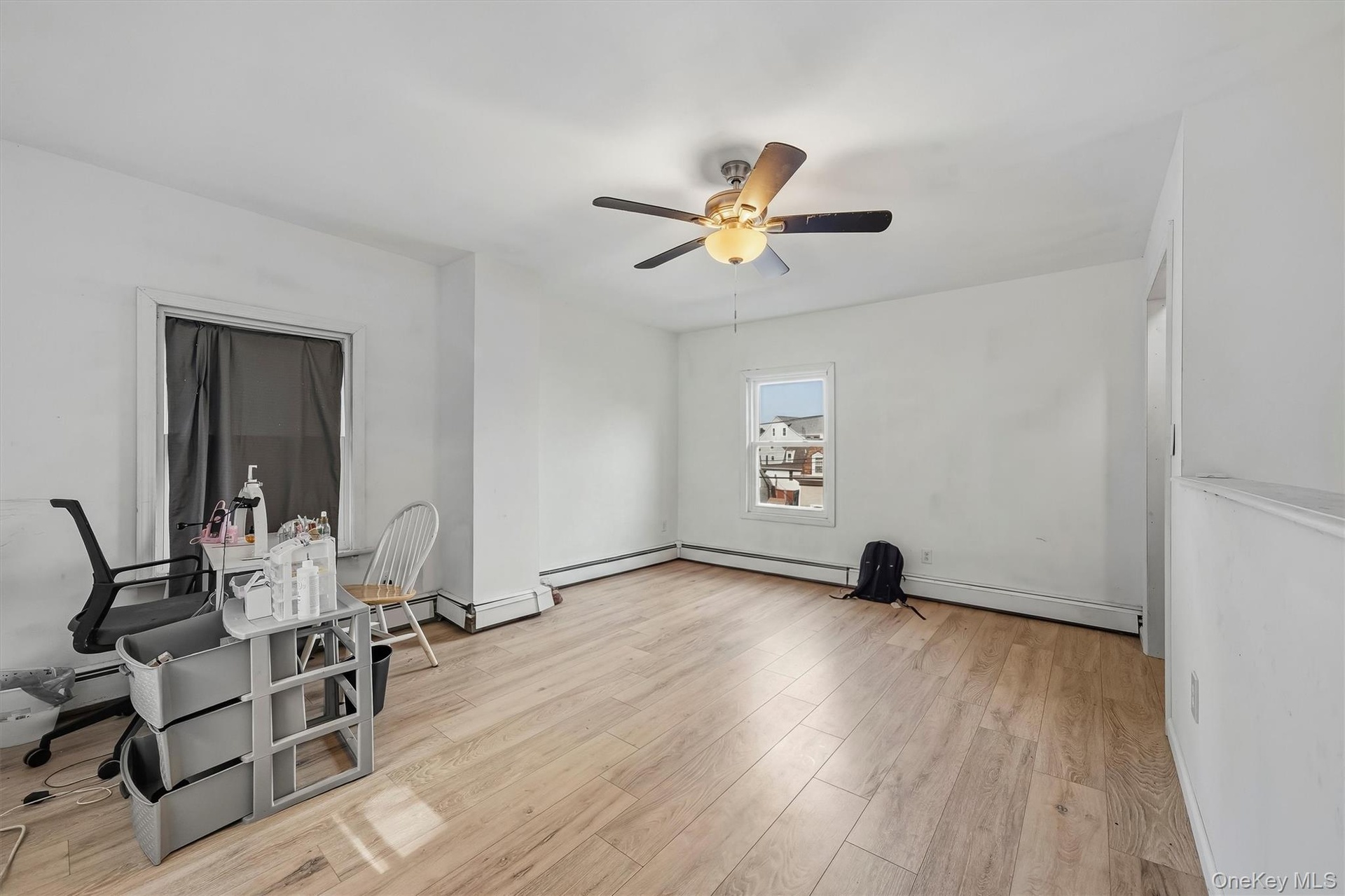 Light wood-finish flooring, white painted walls, and a ceiling fan with integrated lighting