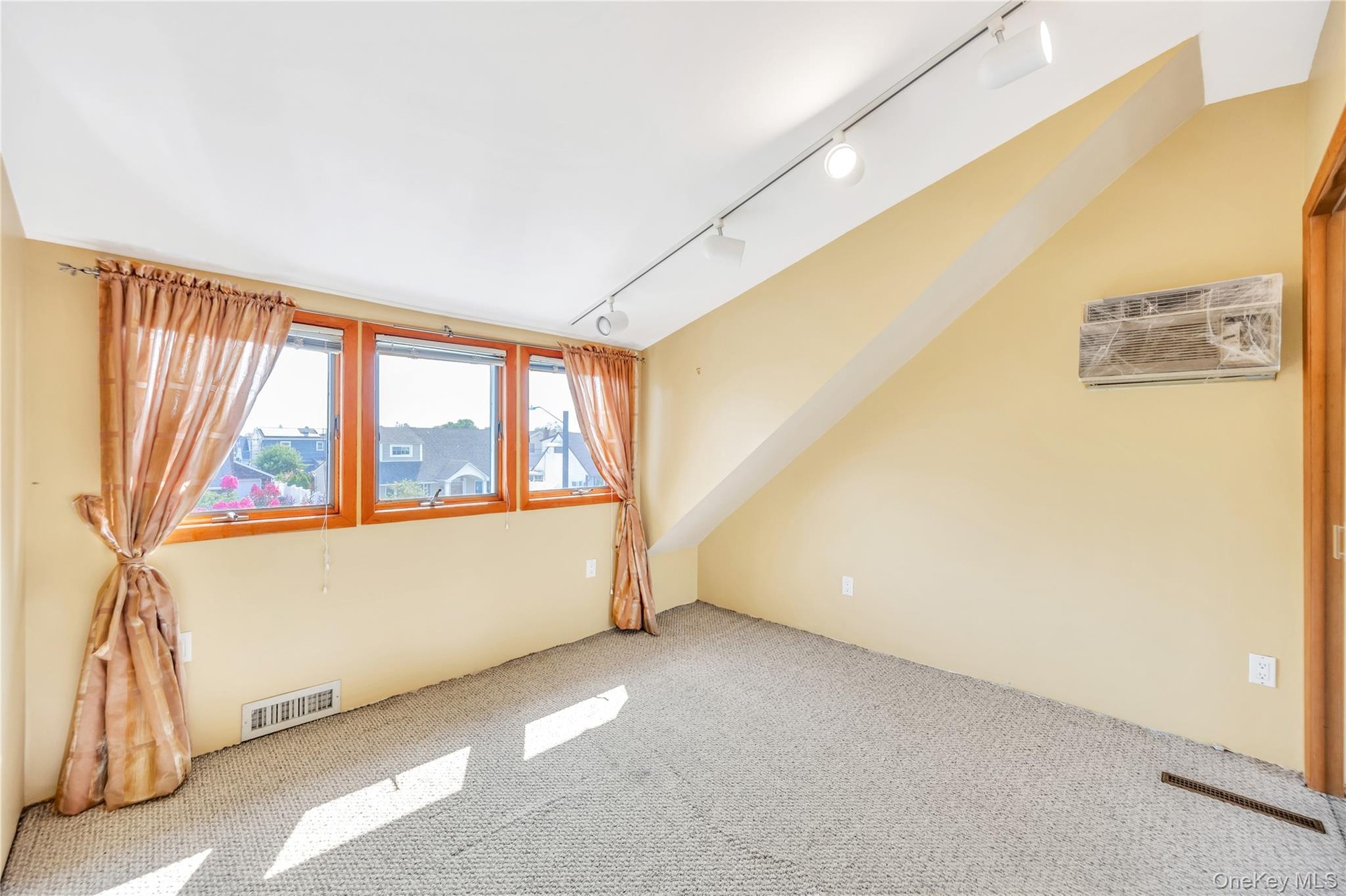 Carpeted spare room with rail lighting and an AC wall unit