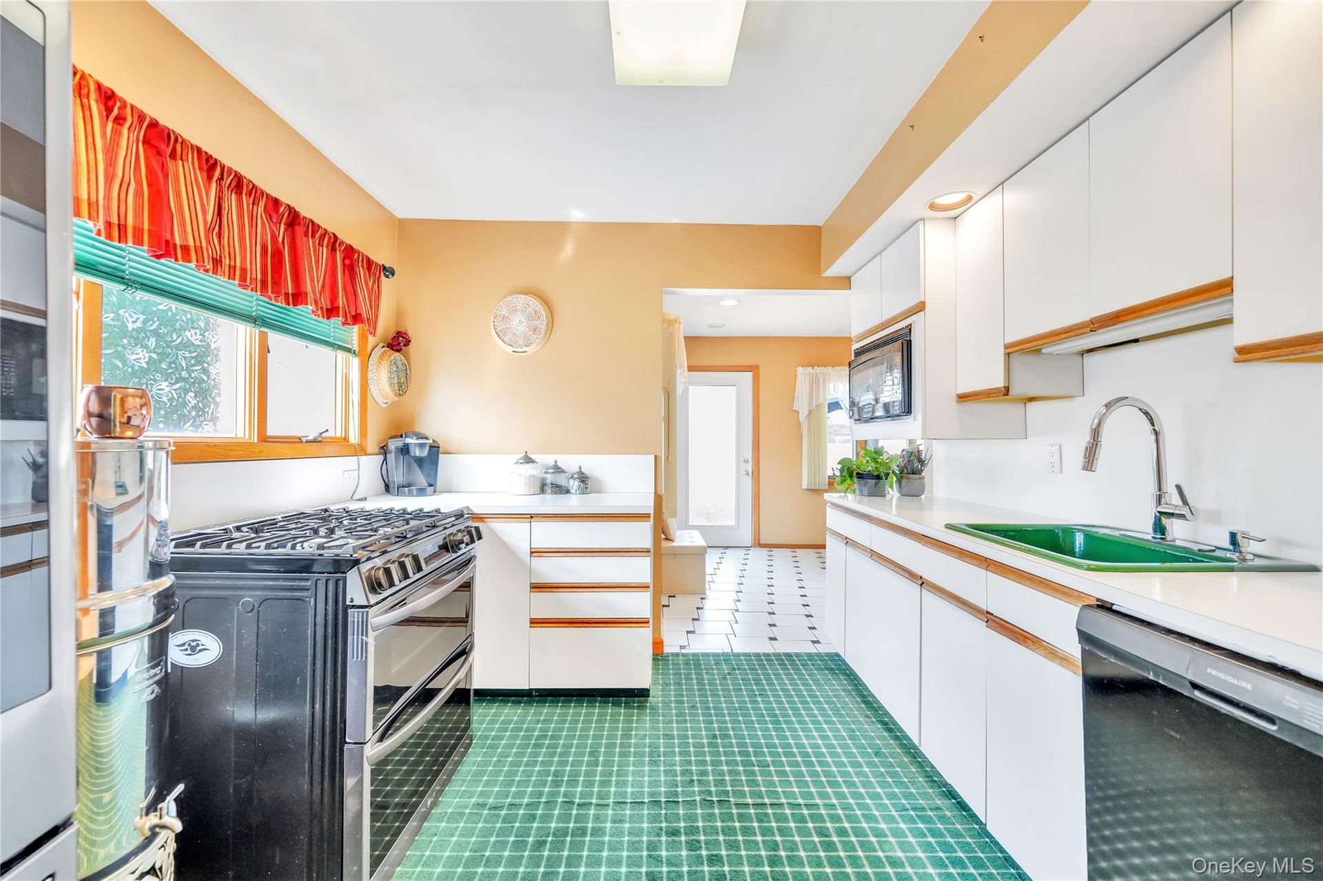 Kitchen with black appliances, white cabinets, light countertops, and tile patterned flooring