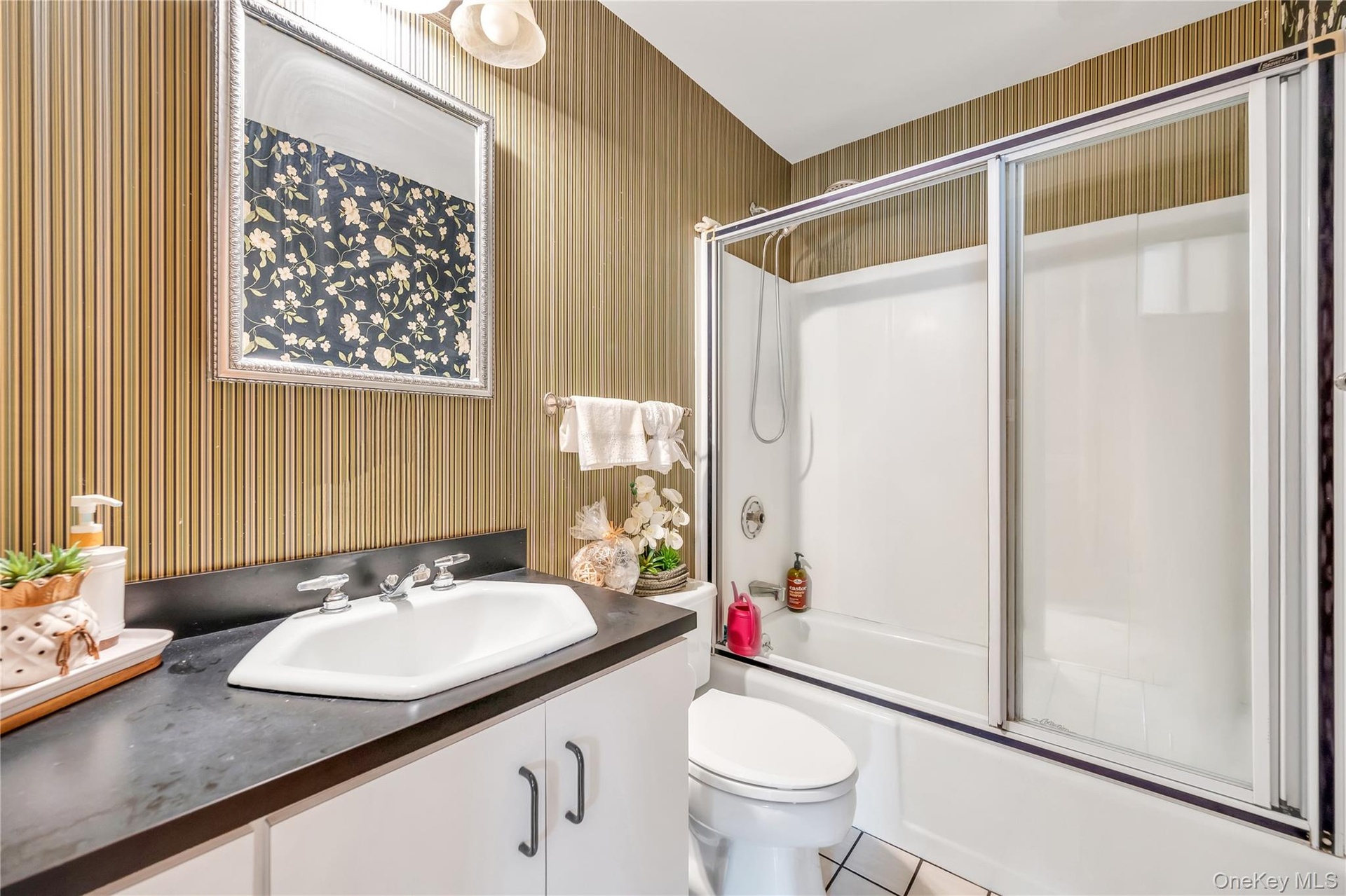 Full bath with wallpapered walls, vanity, combined bath / shower with glass door, and tile patterned flooring