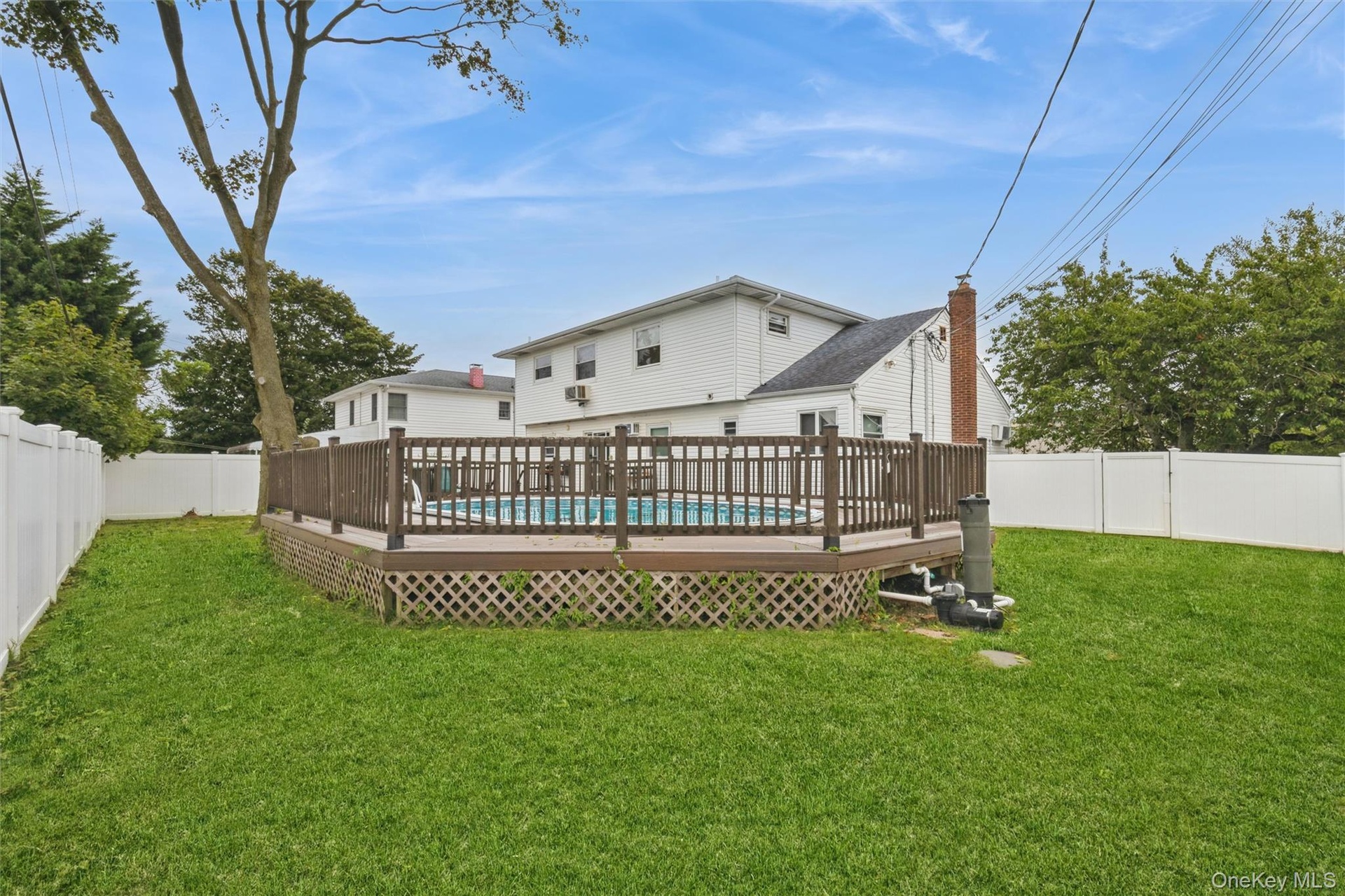 Yard spaces around permitted partially inground pool with fence and trek decking surrounding