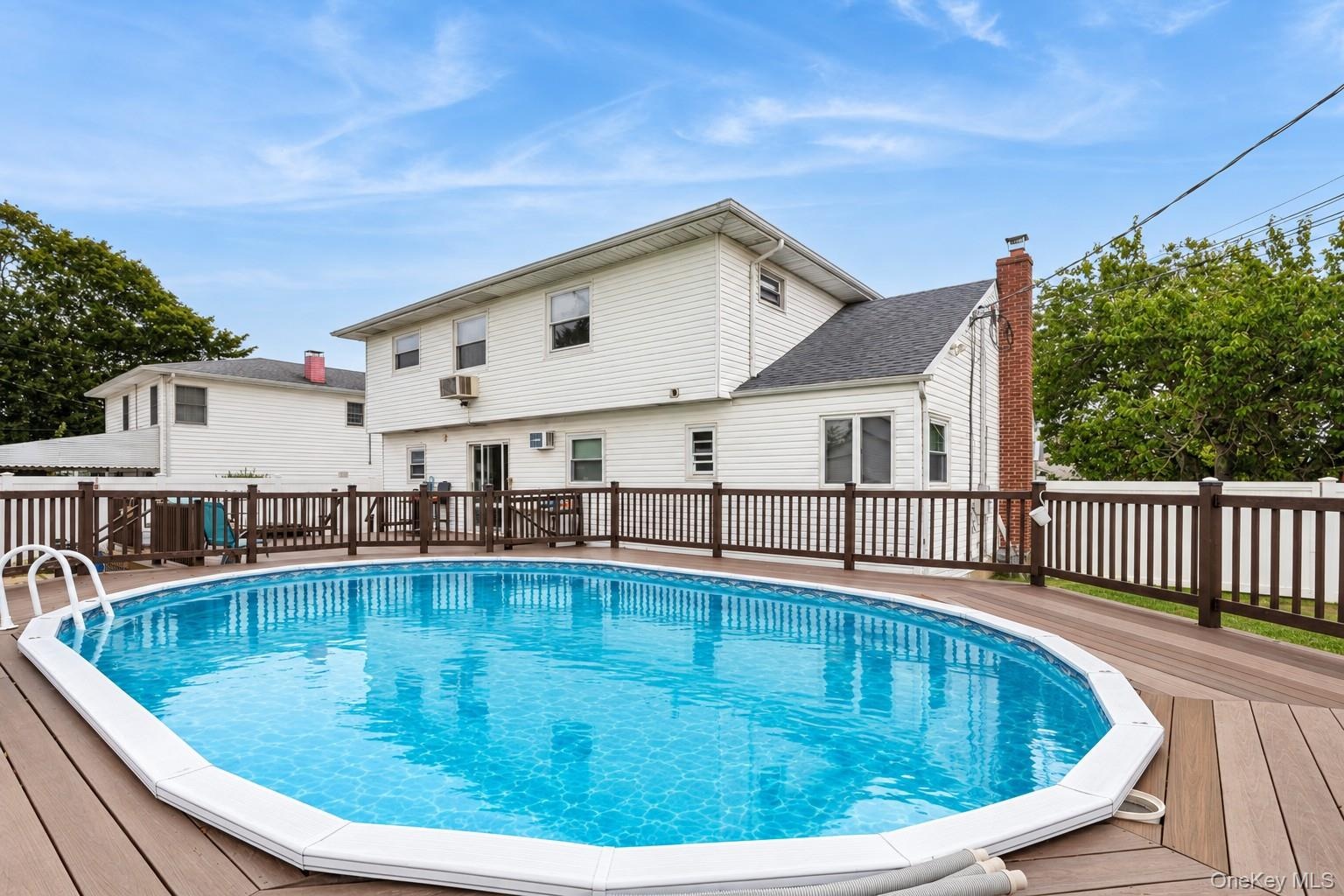 Permitted partially inground pool with fence and trek decking surrounding (virtually enhanced)