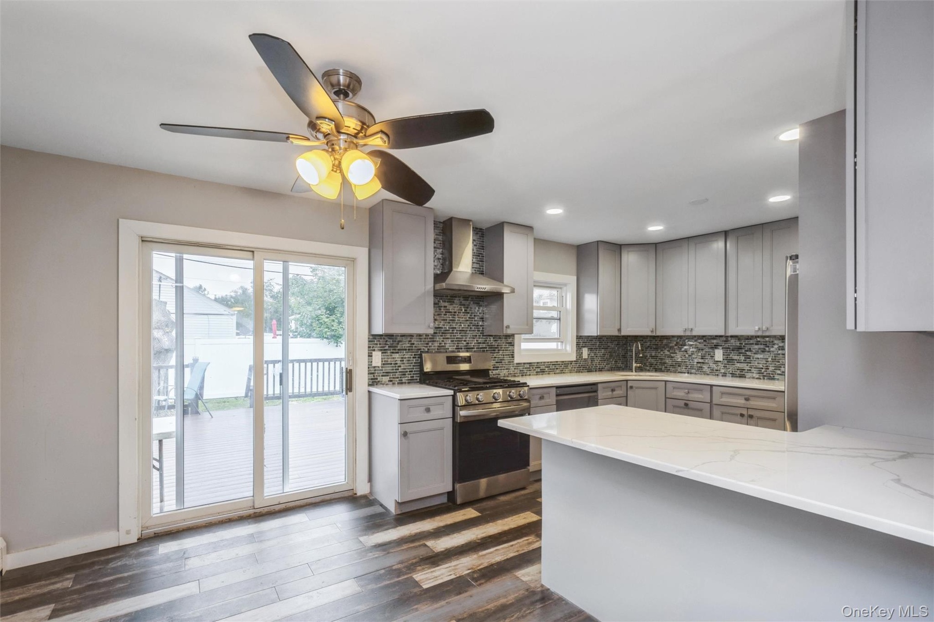 First floor renovated kitchen with quartz counter tops and stainless steel appliances. Sliders to deck in yard.