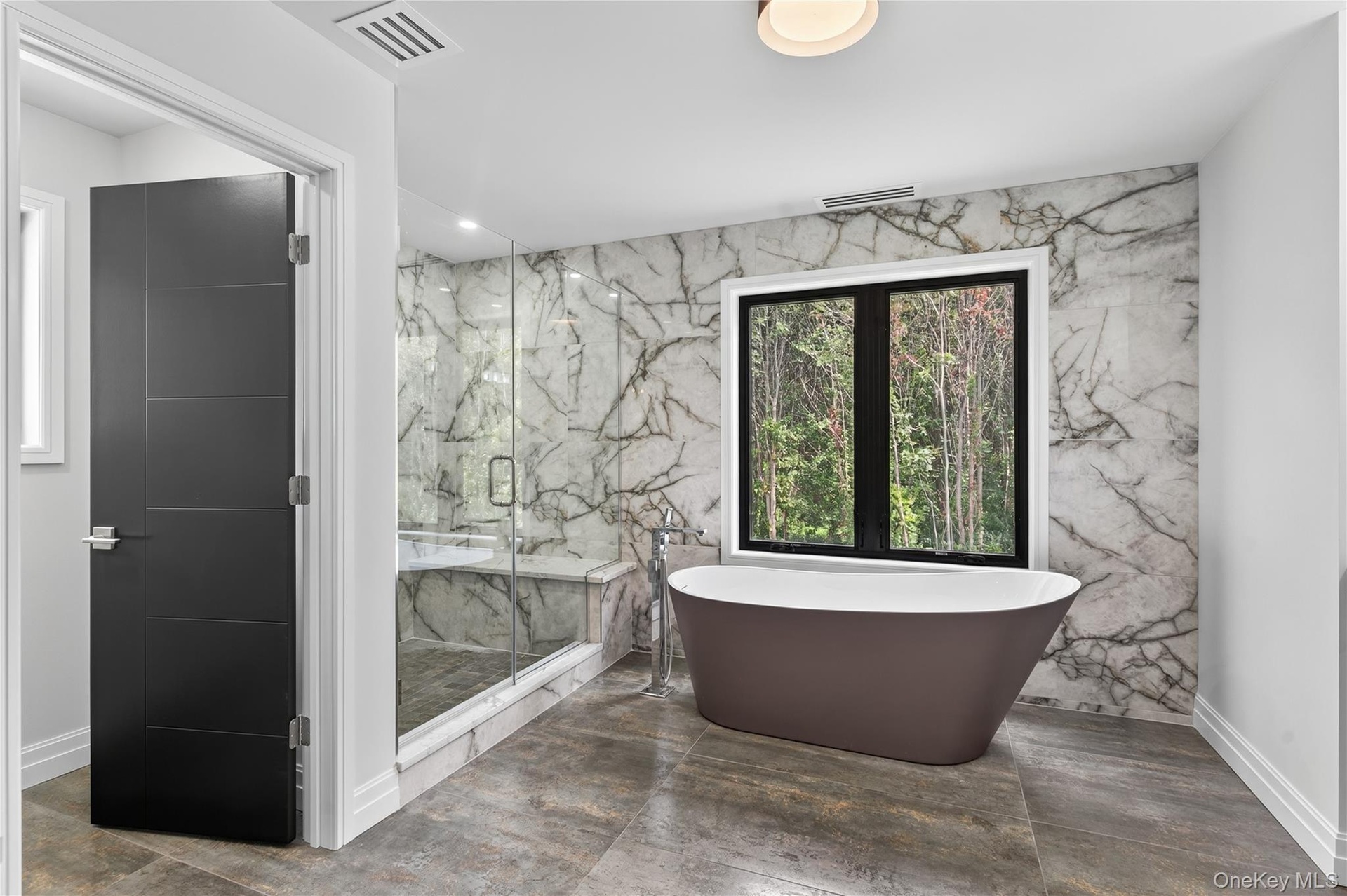 Bathroom with a marble finish shower, a freestanding tub, and recessed lighting