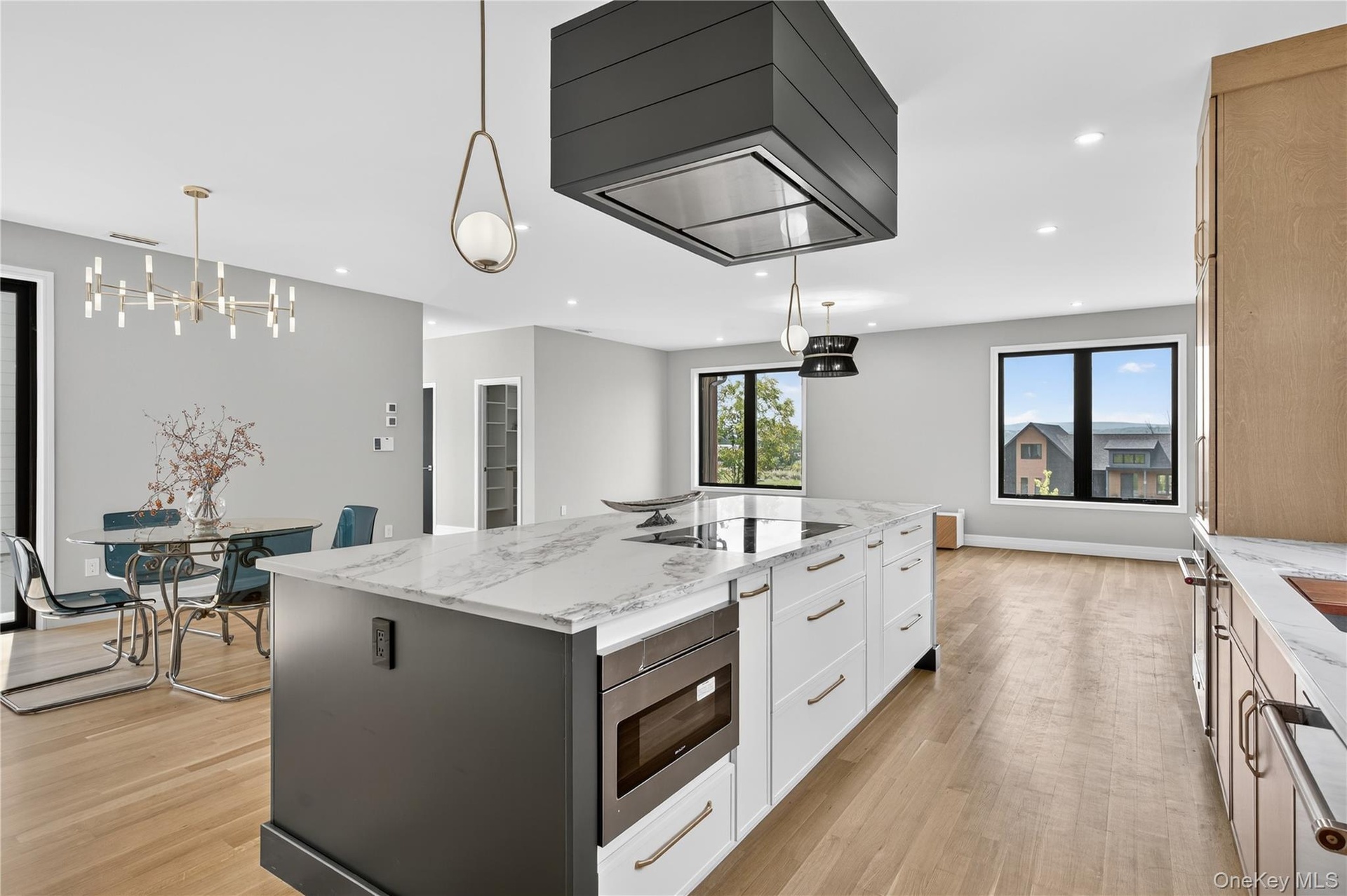 Kitchen with light stone counters, pendant lighting, premium range hood, light wood-style floors, and recessed lighting