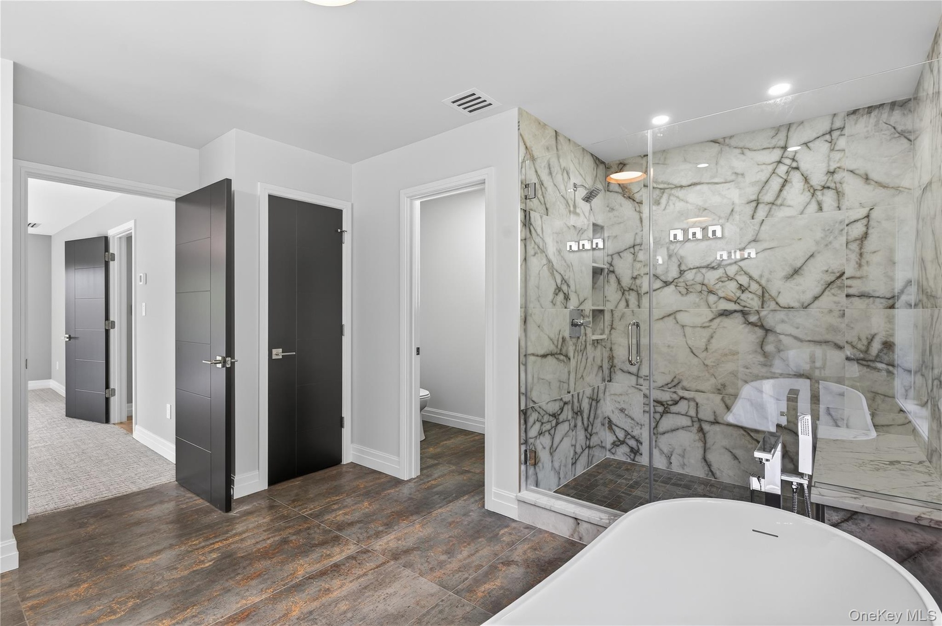 Bathroom featuring a freestanding bath, a marble finish shower, recessed lighting, and dark wood-style flooring